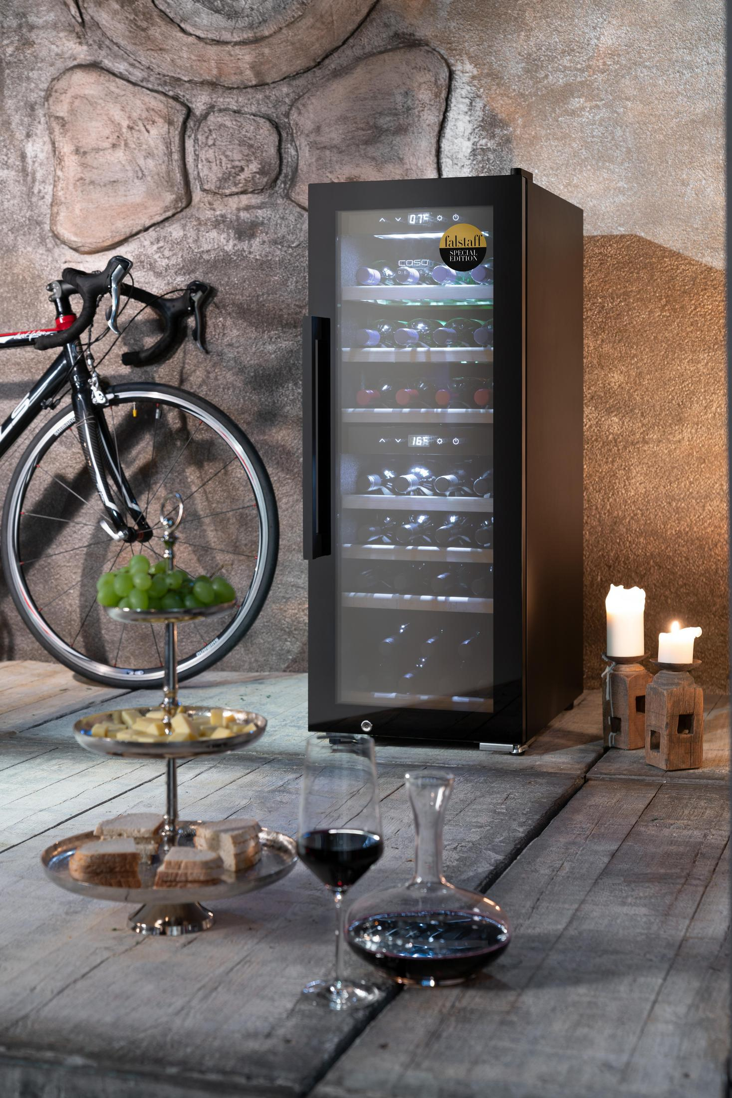 Weinkühler mit Weinflaschen, Fahrrad, Käseplatte und Weingläsern auf Holzboden.