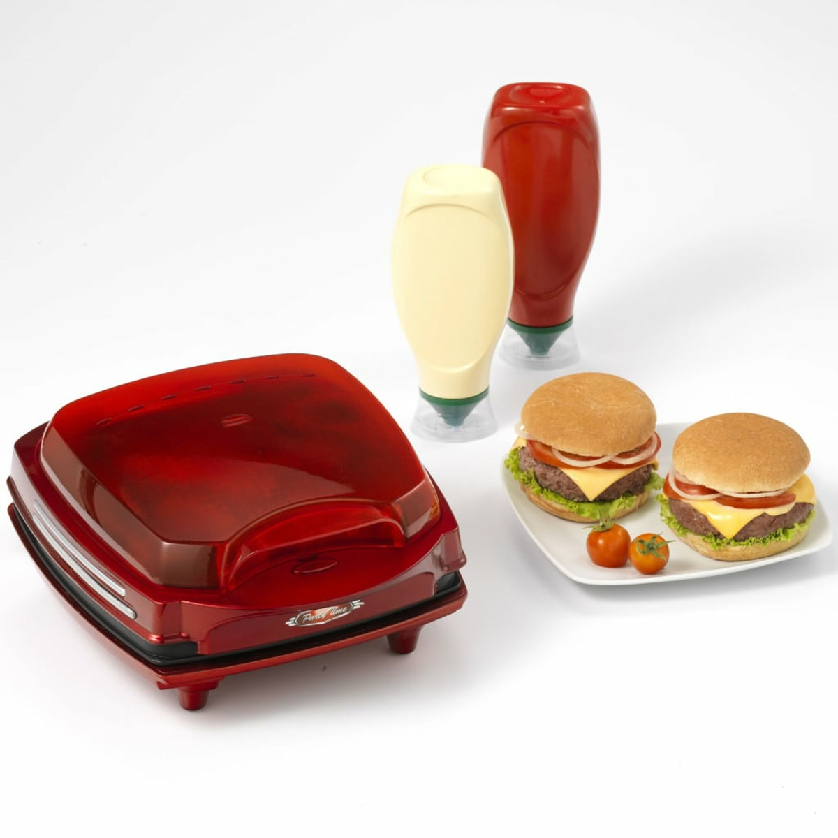 Una pressa per hamburger rossa con ketchup, bottiglie di maionese e due hamburger su un piatto. Pomodorini.