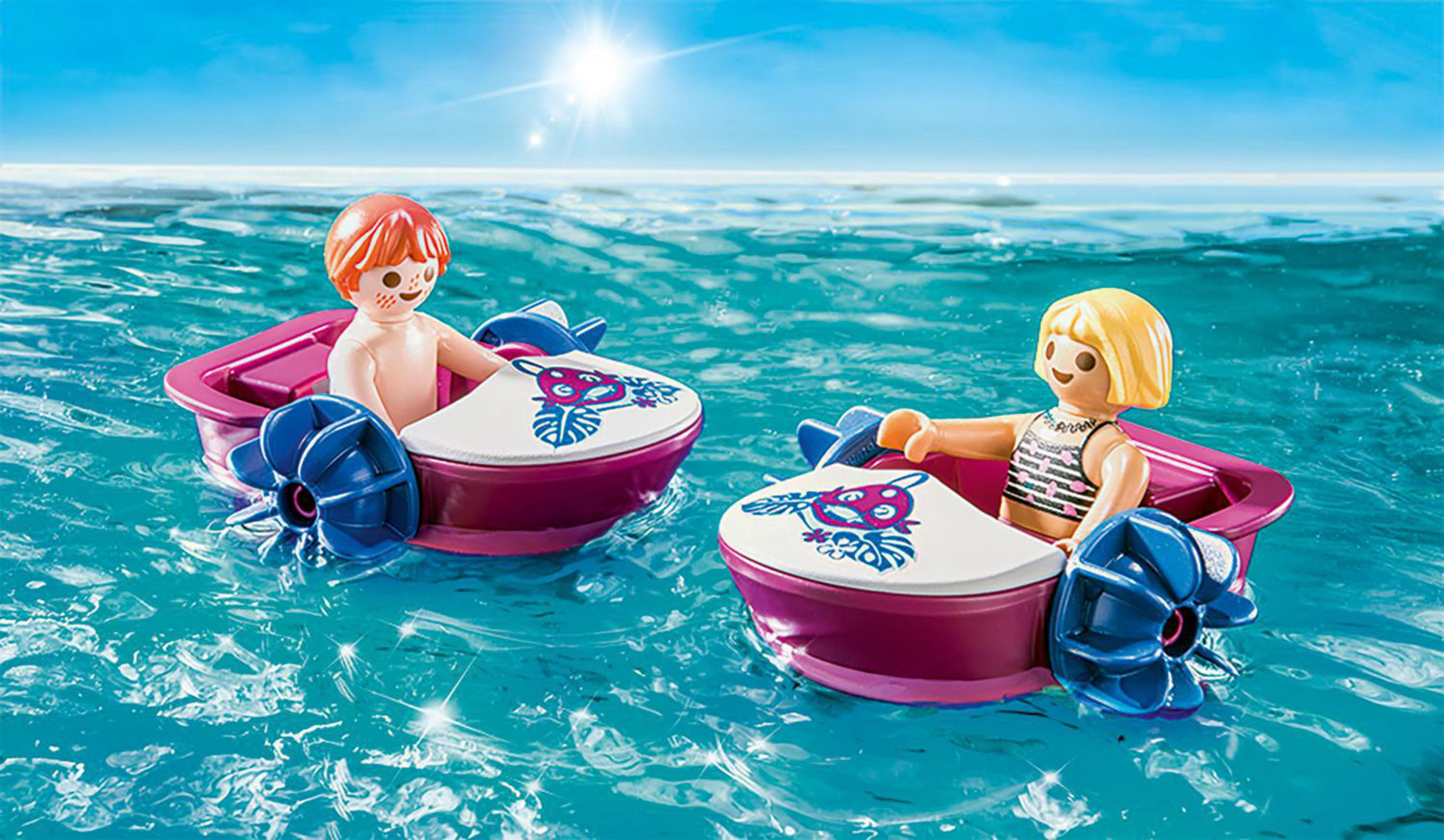 Zwei Spielzeugboote mit Kinderfiguren, die auf dem Wasser schwimmen.