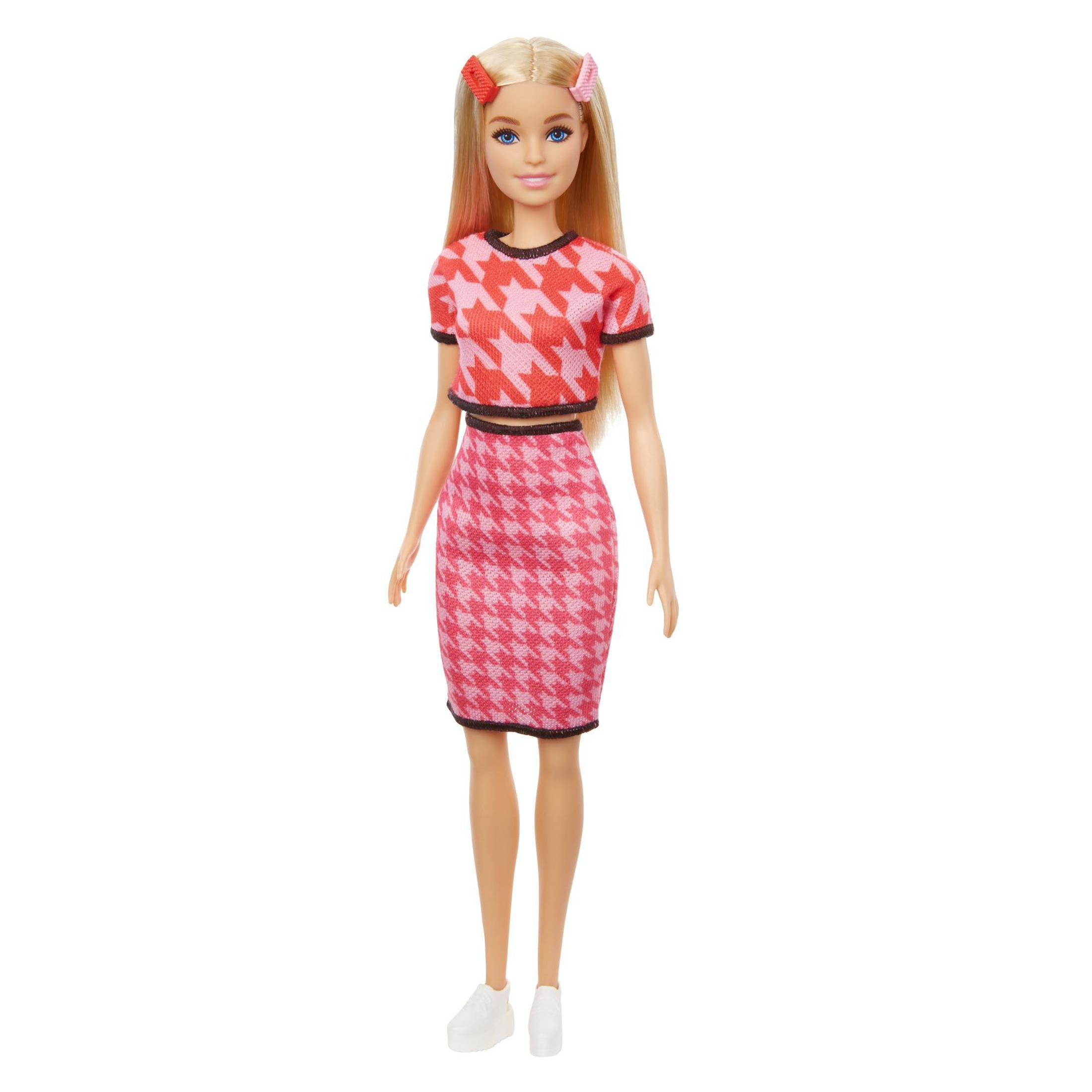 Una muñeca Barbie con top y falda estampados en rojo y rosa, con zapatos blancos y pinzas rosas.