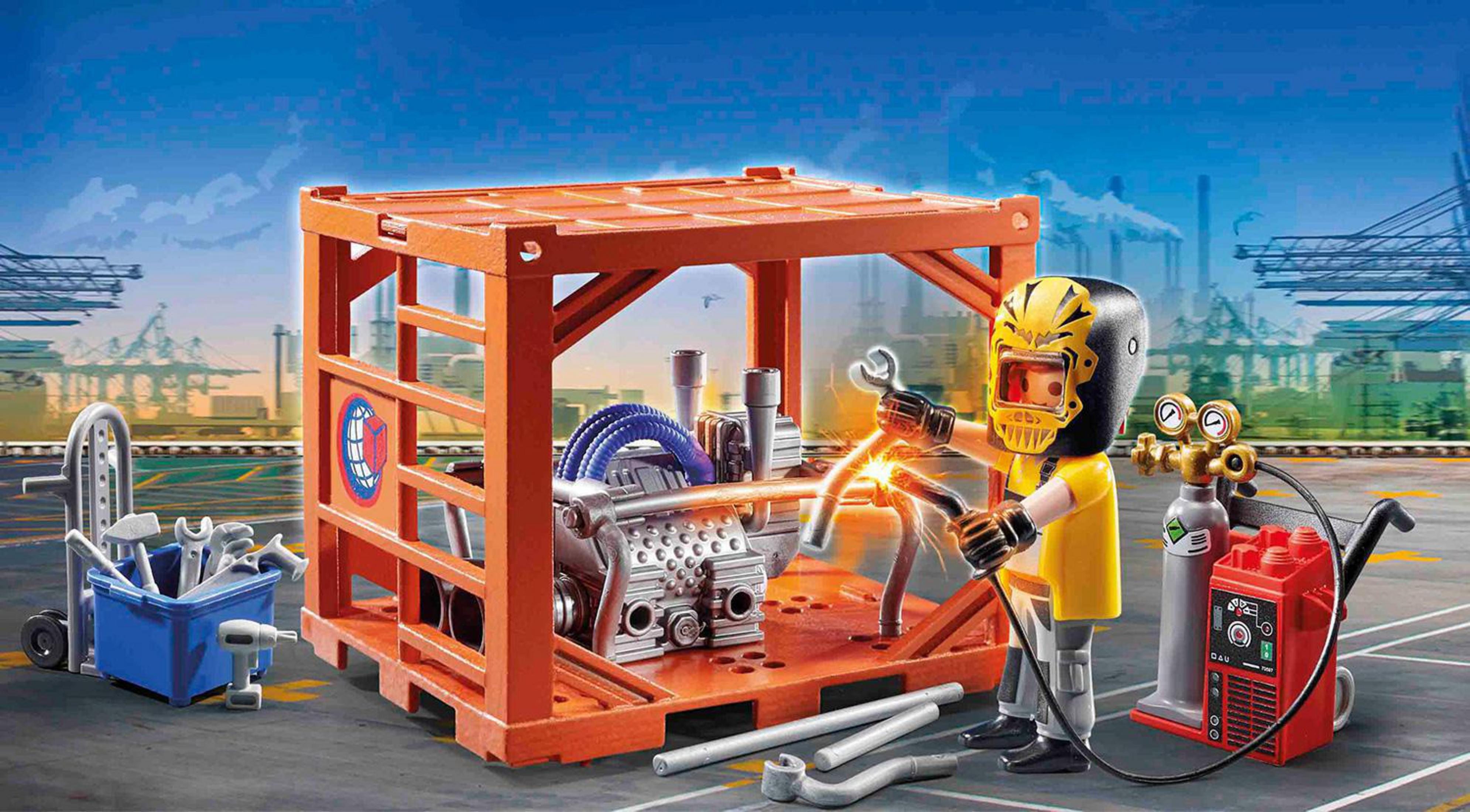 Spielfigur beim Schweißen eines Motors. Oranger Container und Werkzeuge im Bild.