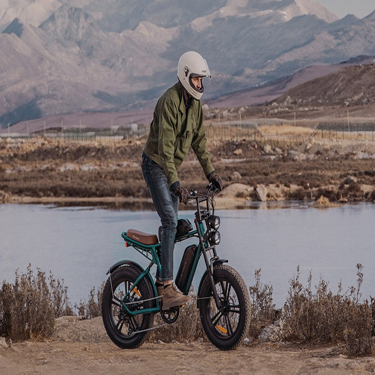 Person fährt ein E-Bike in Berglandschaft. Der Himmel ist bedeckt. Das Fahrrad ist grün und schwarz.