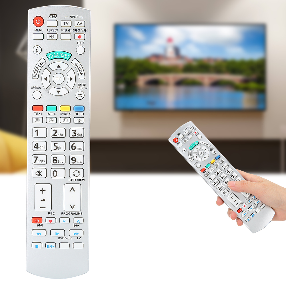 Eine Person hält eine Fernbedienung vor einem Fernseher.