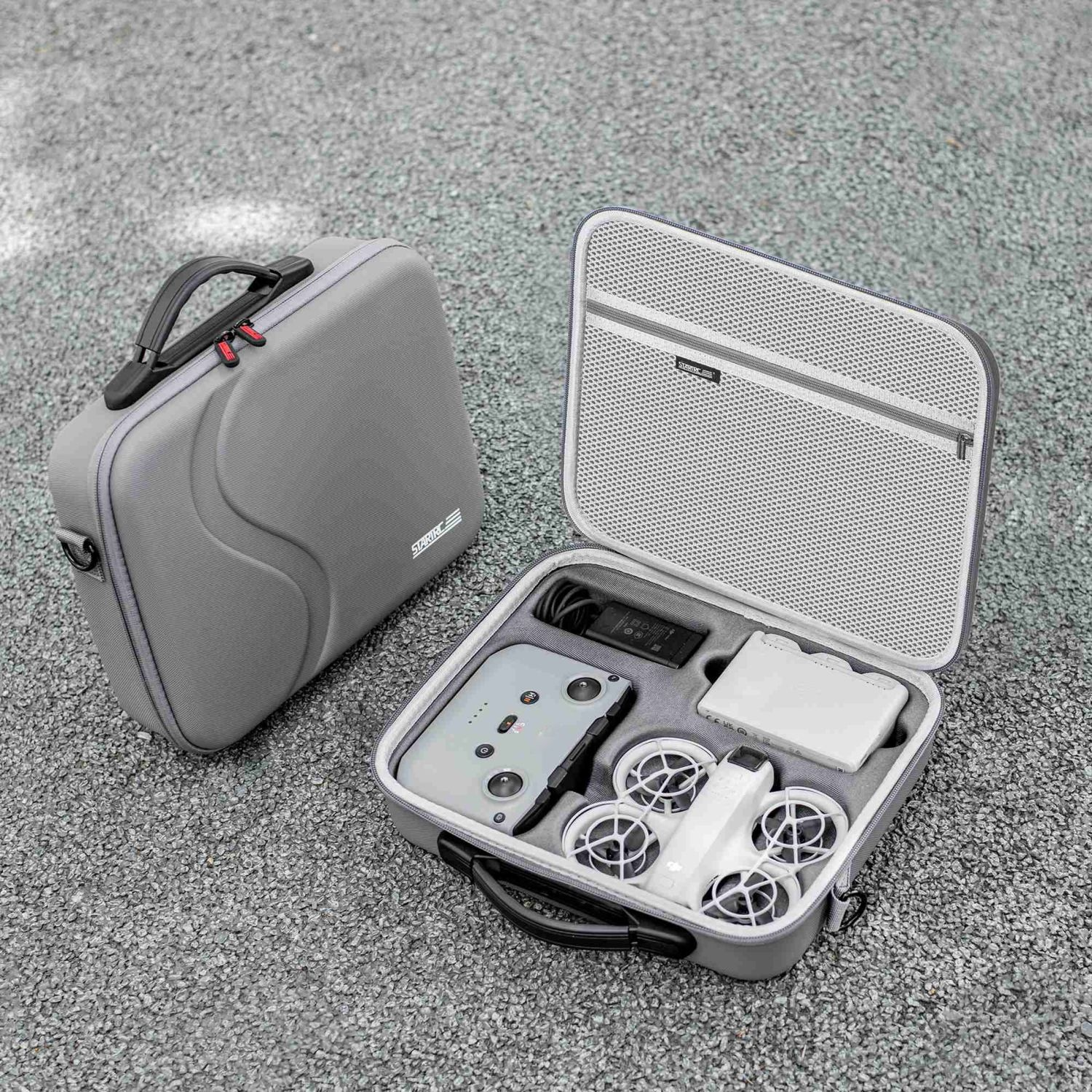 Una custodia grigia per droni, aperta, con drone, controller e accessori. Un'altra custodia è chiusa.