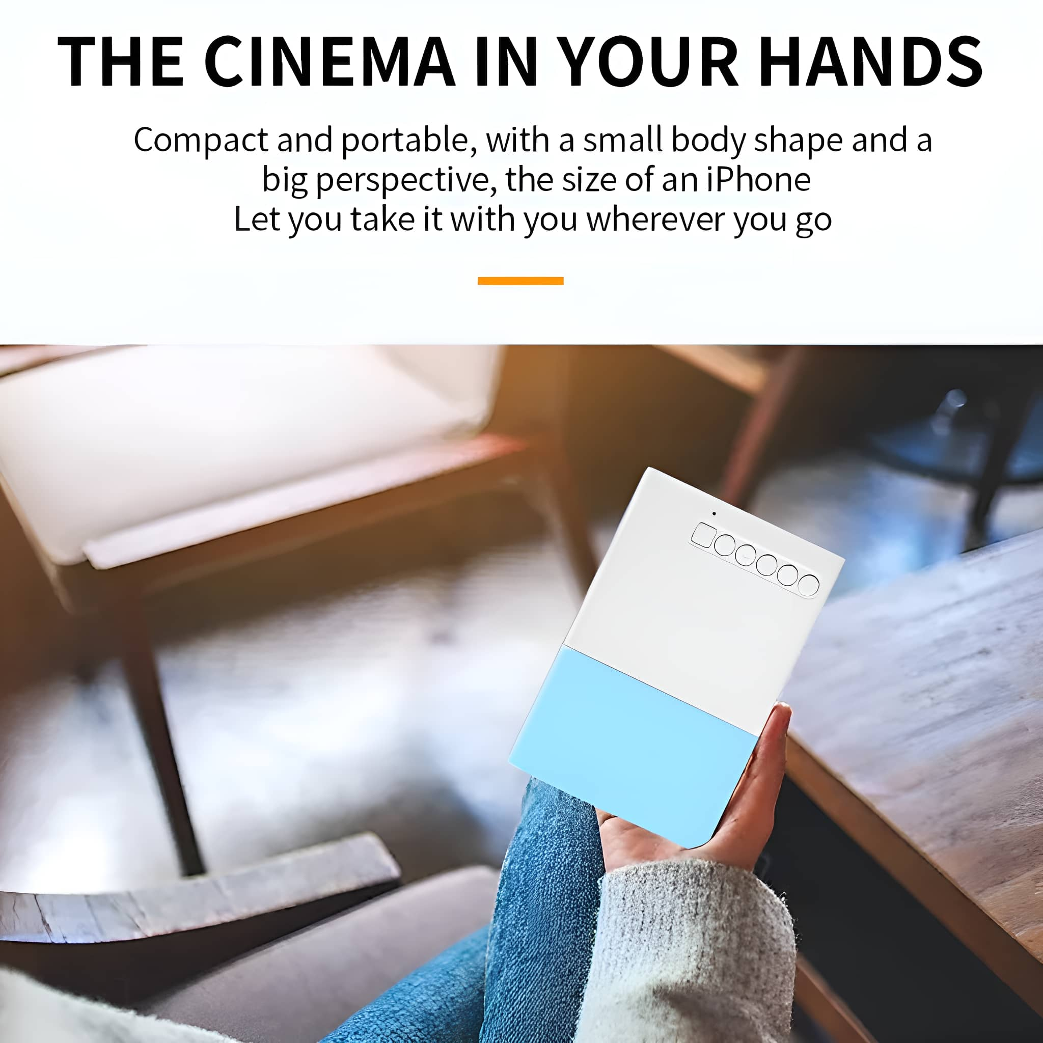 Eine Hand hält einen kleinen weißen und blauen Projektor, mit einem Holztisch.