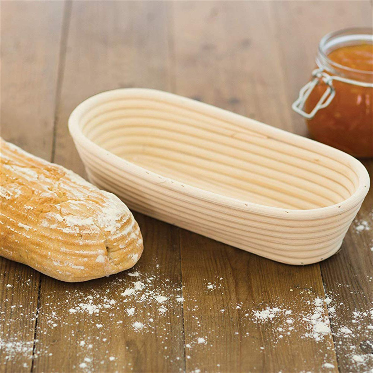 Ein Brotkorb aus Holz neben einem Brotlaib und einem Glas Marmelade auf einer Holzoberfläche.