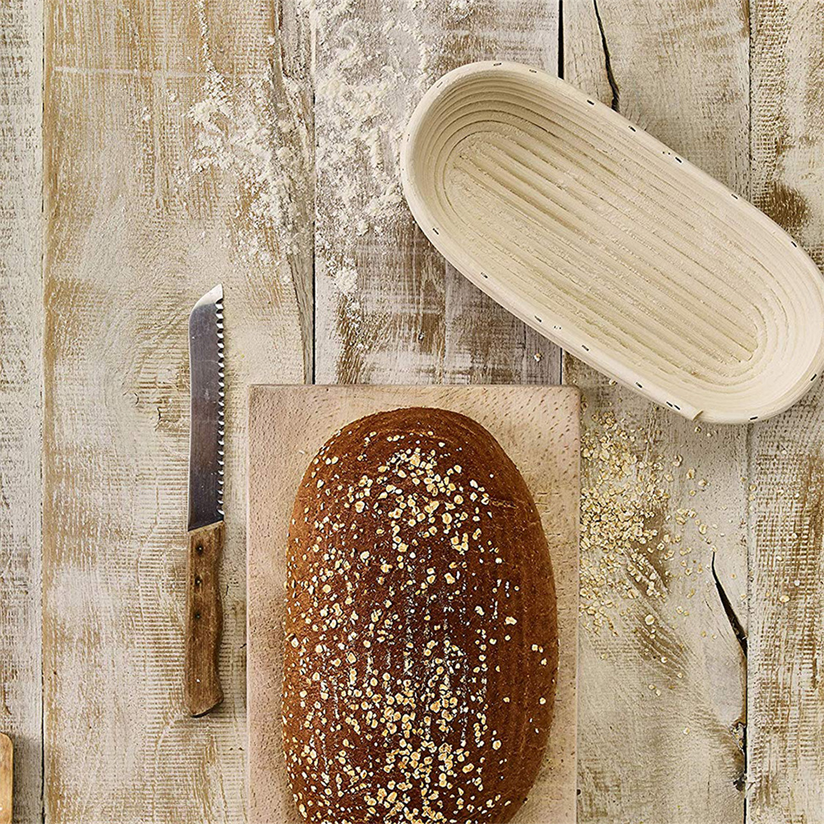 Laib Brot, Messer und Korb auf Holzoberfläche. Mehl verstreut. Draufsicht.