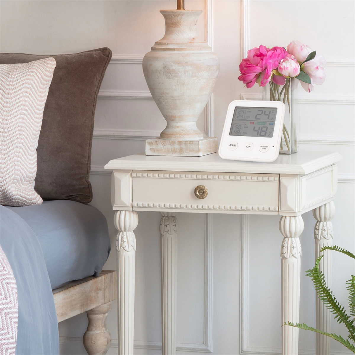 Nachttisch mit Digitaluhr, Blumen und Lampe. Eine gemütliche Schlafzimmerumgebung.