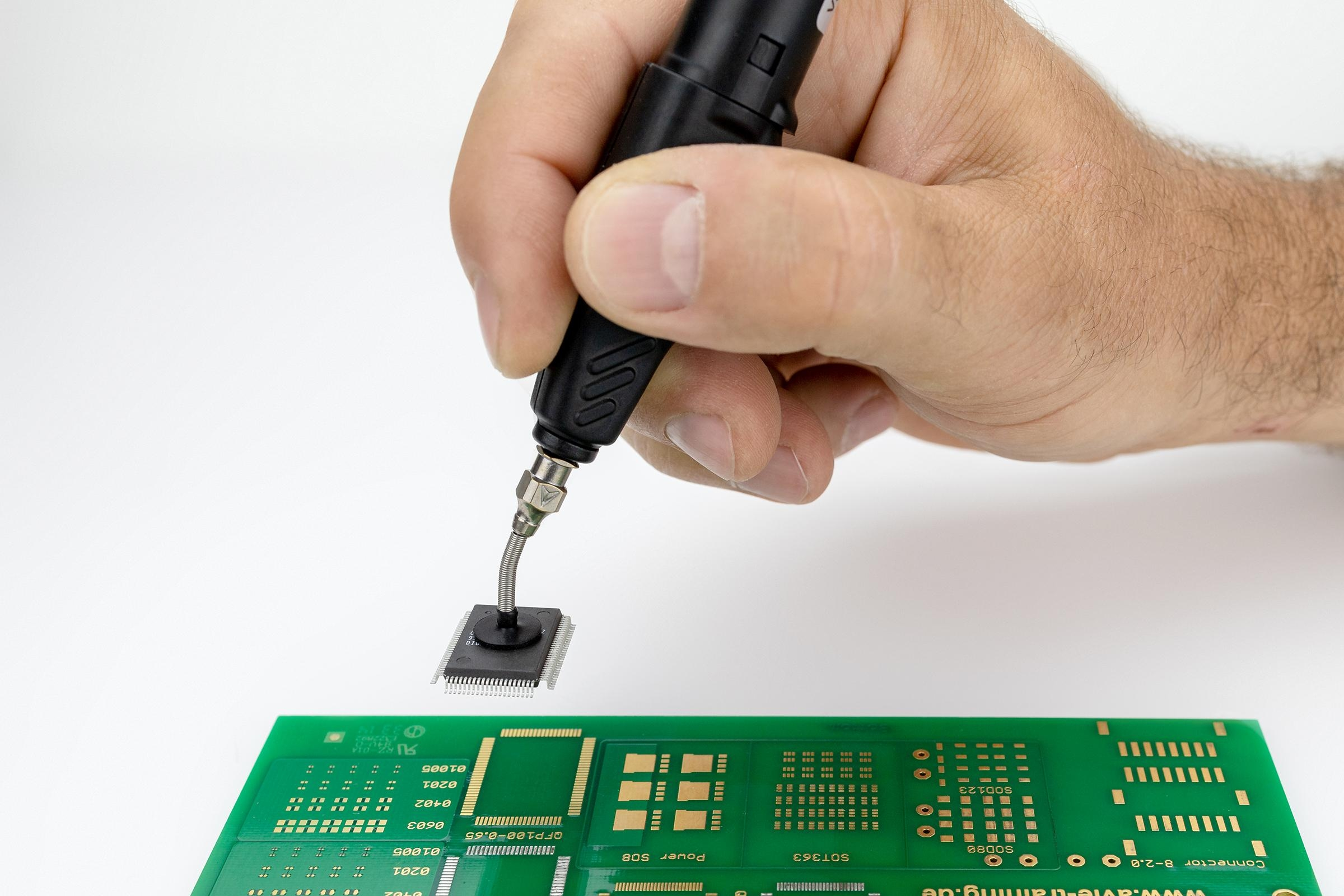Eine Hand, die eine kleine elektronische Komponente lötet.