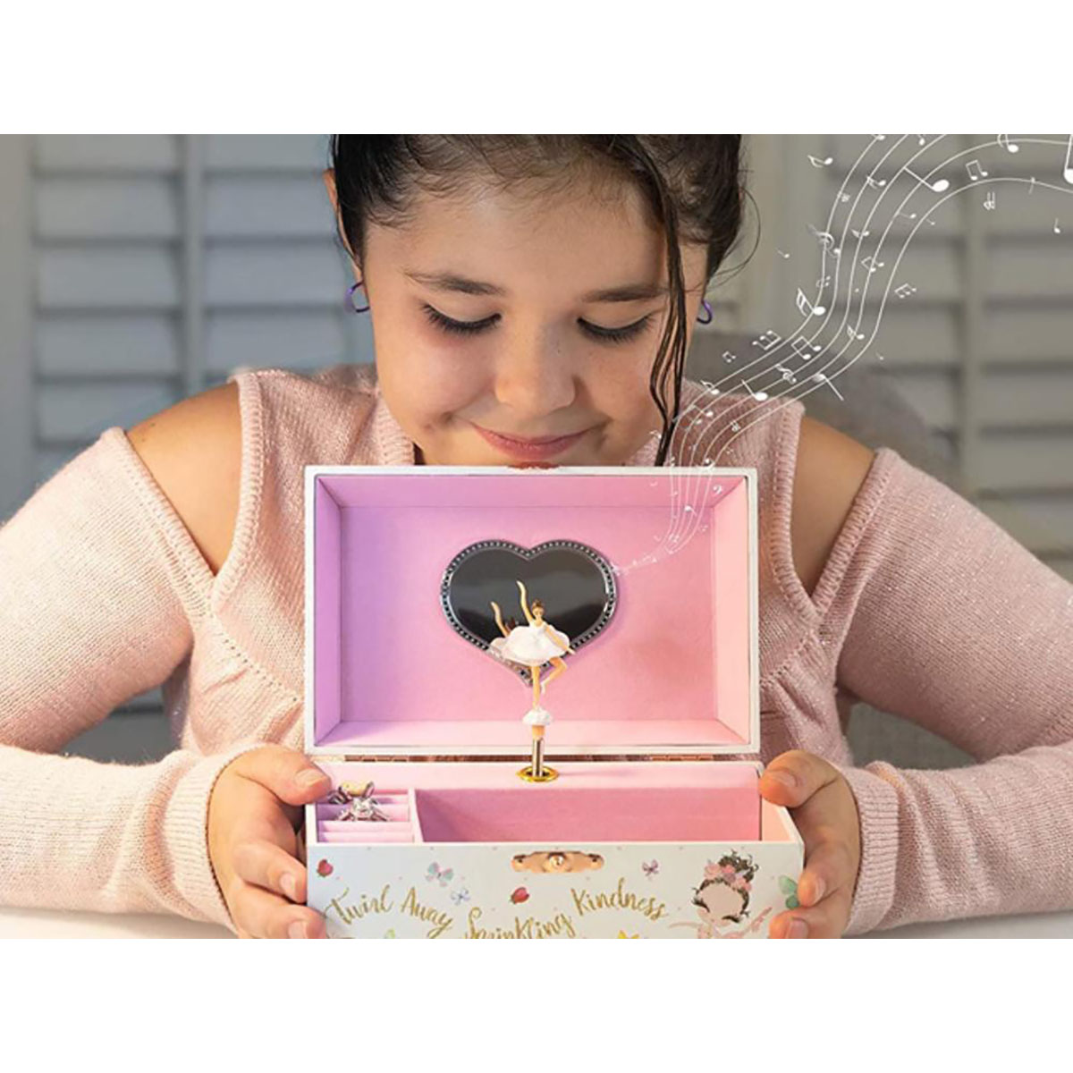 Ragazza guarda carillon con ballerina. Note musicali intorno. Sfondo bianco.