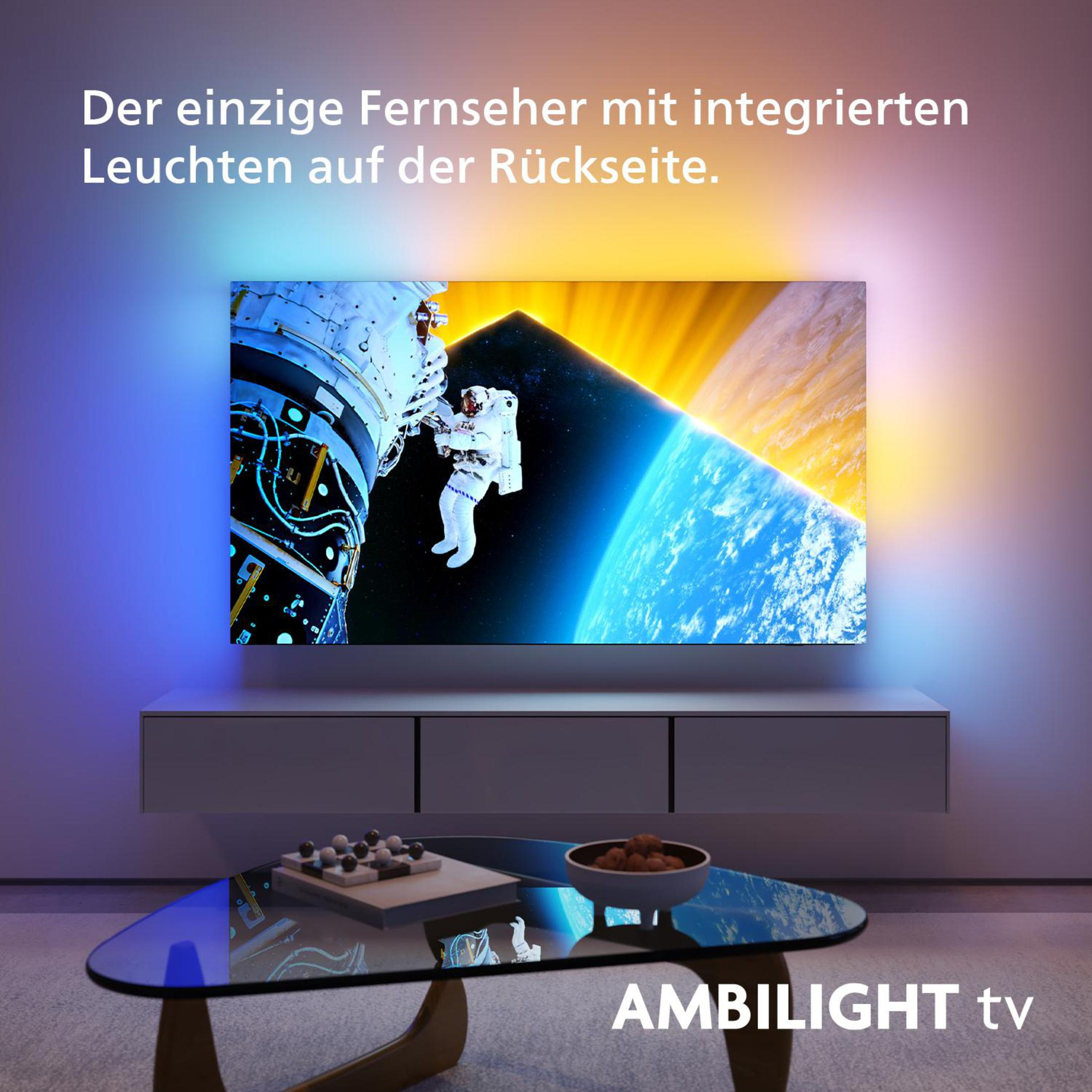 Fernseher mit Astronautenbild, umgeben von blauen und gelben Lichtern auf einem Schrank.