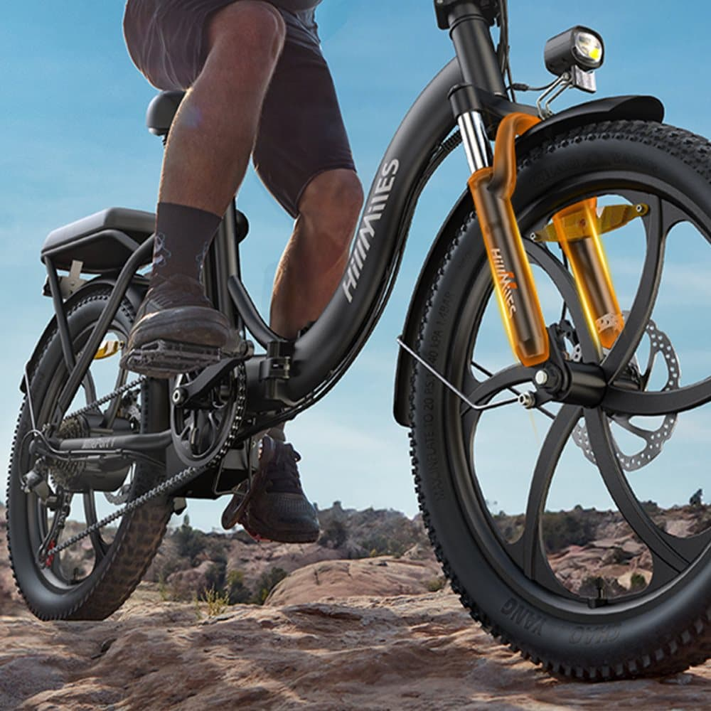 Persona che guida una bicicletta elettrica su un terreno roccioso, con sospensioni arancioni.