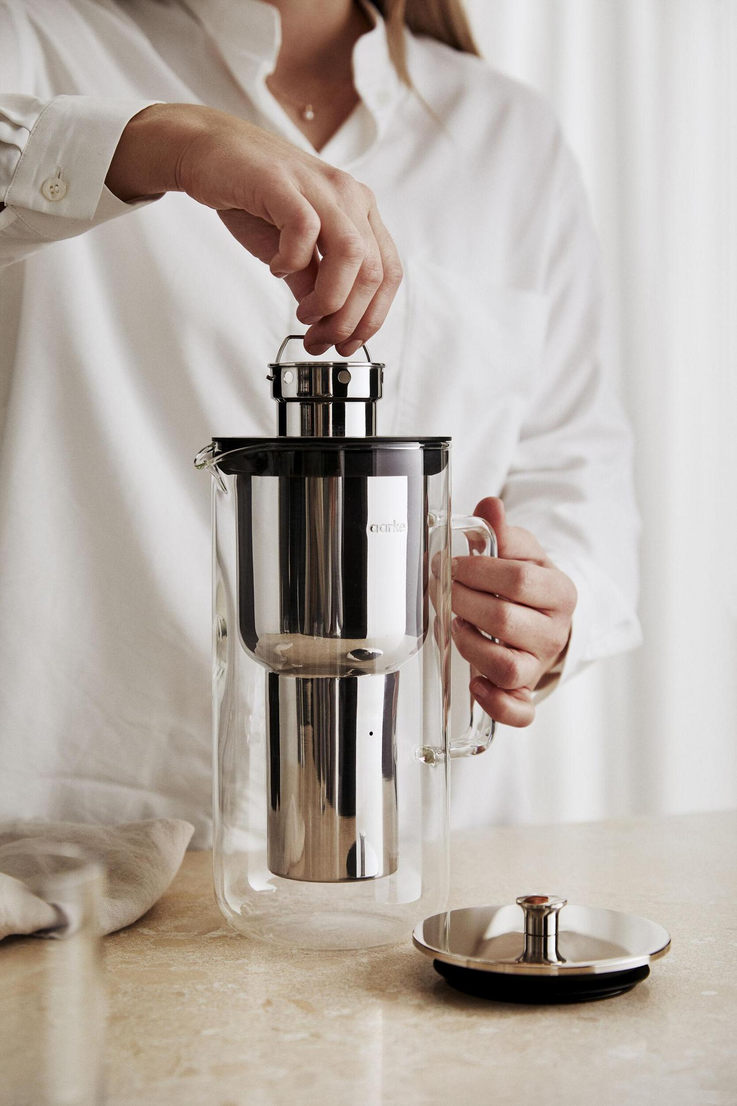 Osoba nalewająca coś z metalowego pojemnika.