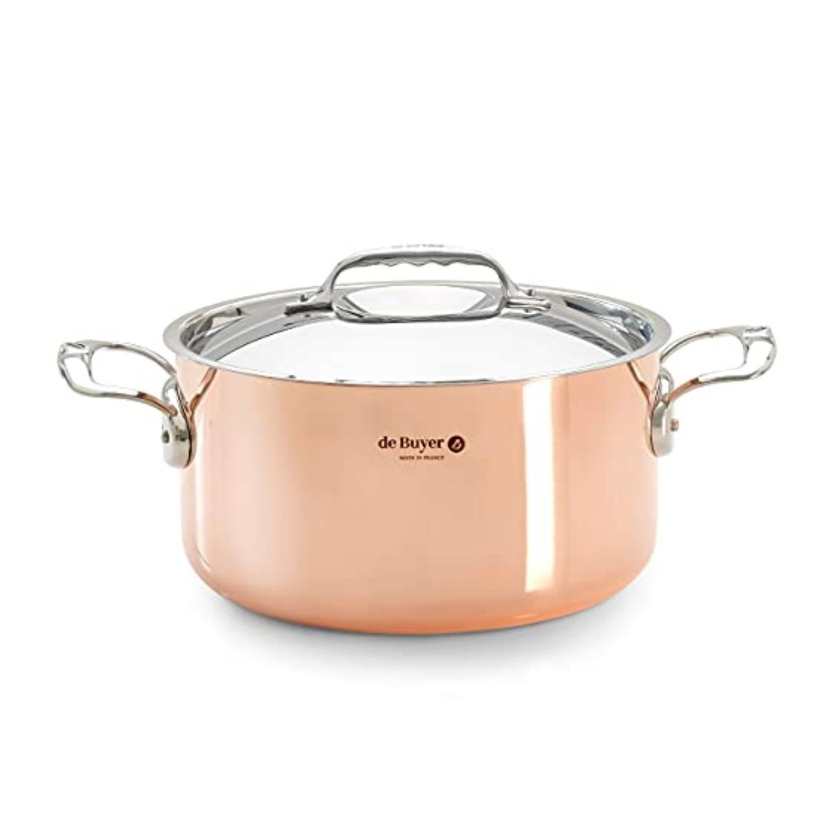 Miedziany garnek z pokrywką i uchwytami. Garnek ma srebrną krawędź. Białe tło.