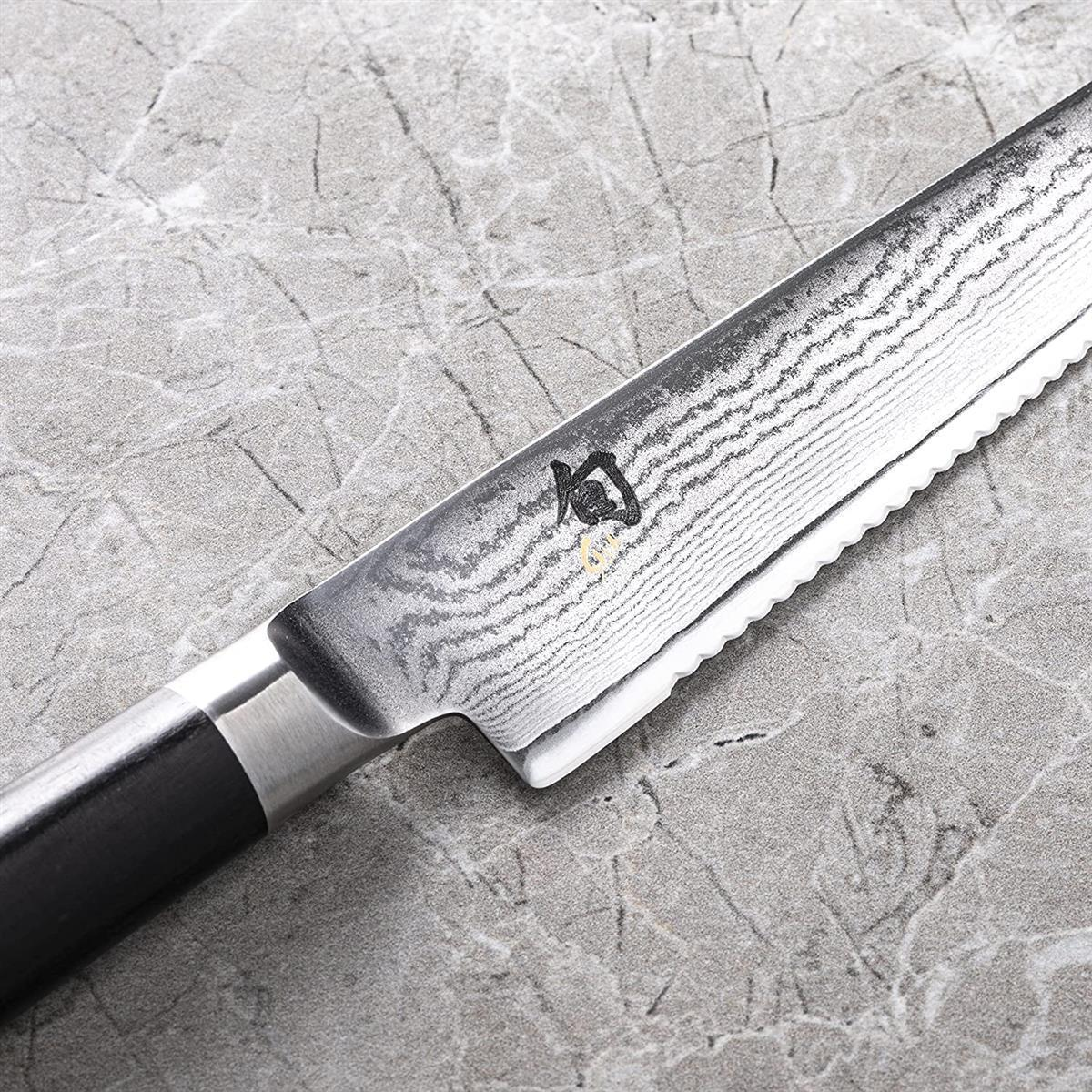 Zbliżenie ostrza noża o wzorzystej fakturze. Ostrze leży na marmurowej powierzchni.