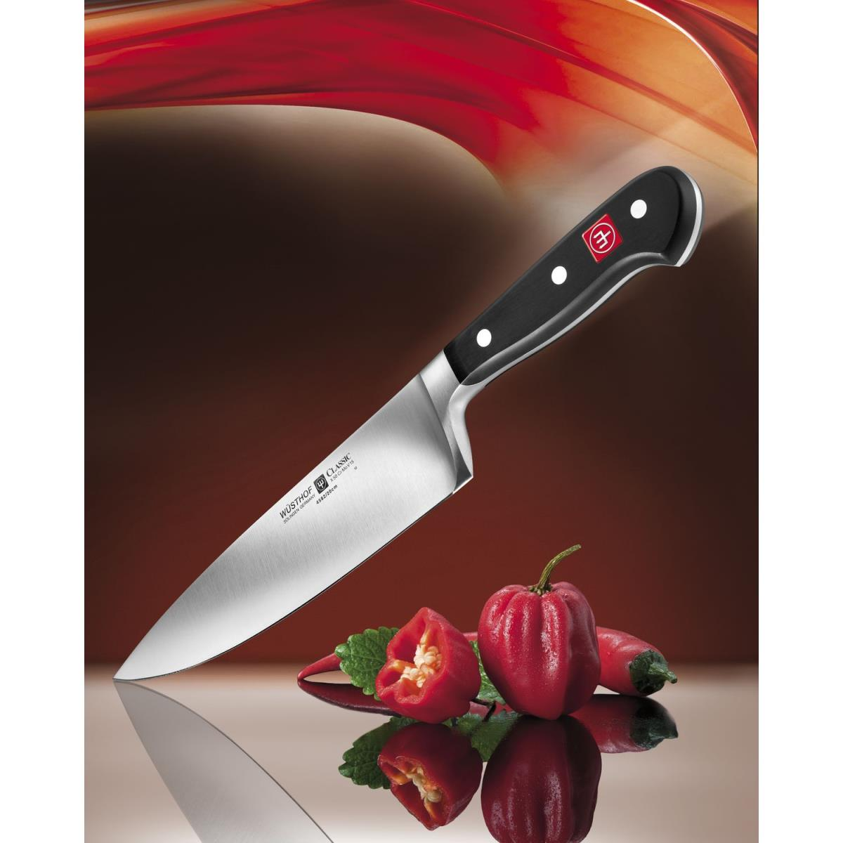 Ein Küchenmesser mit roten Paprika und einer Schneidefläche.