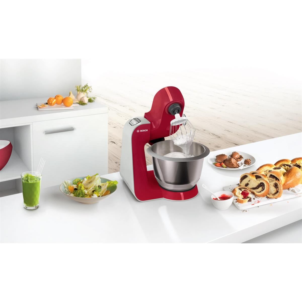 Roter und weißer Standmixer mit Zutaten und Speisen auf einer weißen Theke.