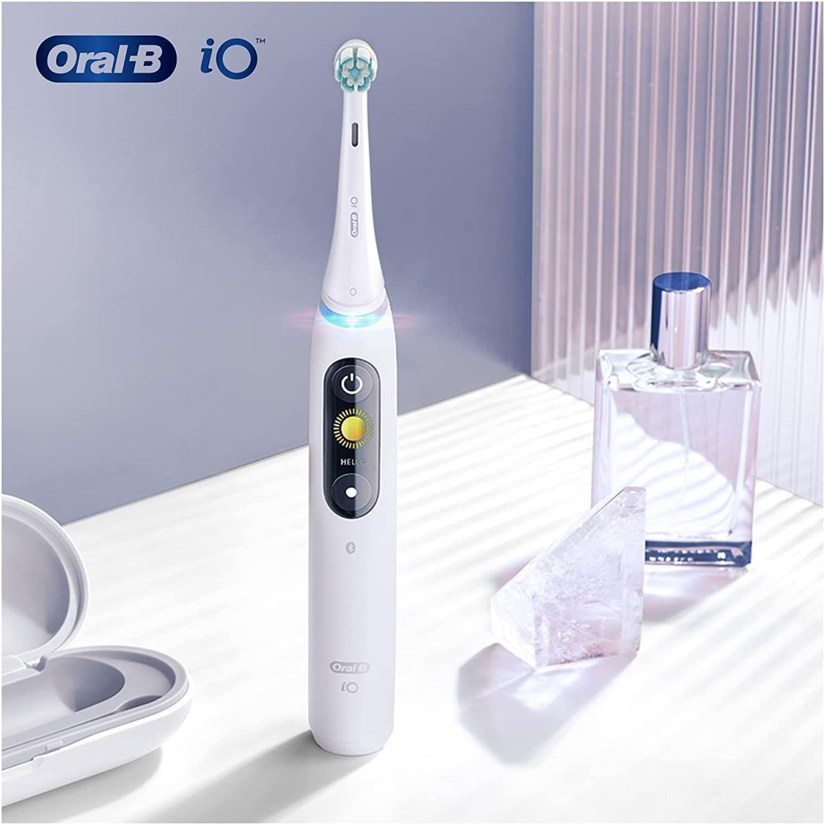 Weiße elektrische Zahnbürste Oral-B iO. Daneben eine Parfümflasche und ein Kristall.