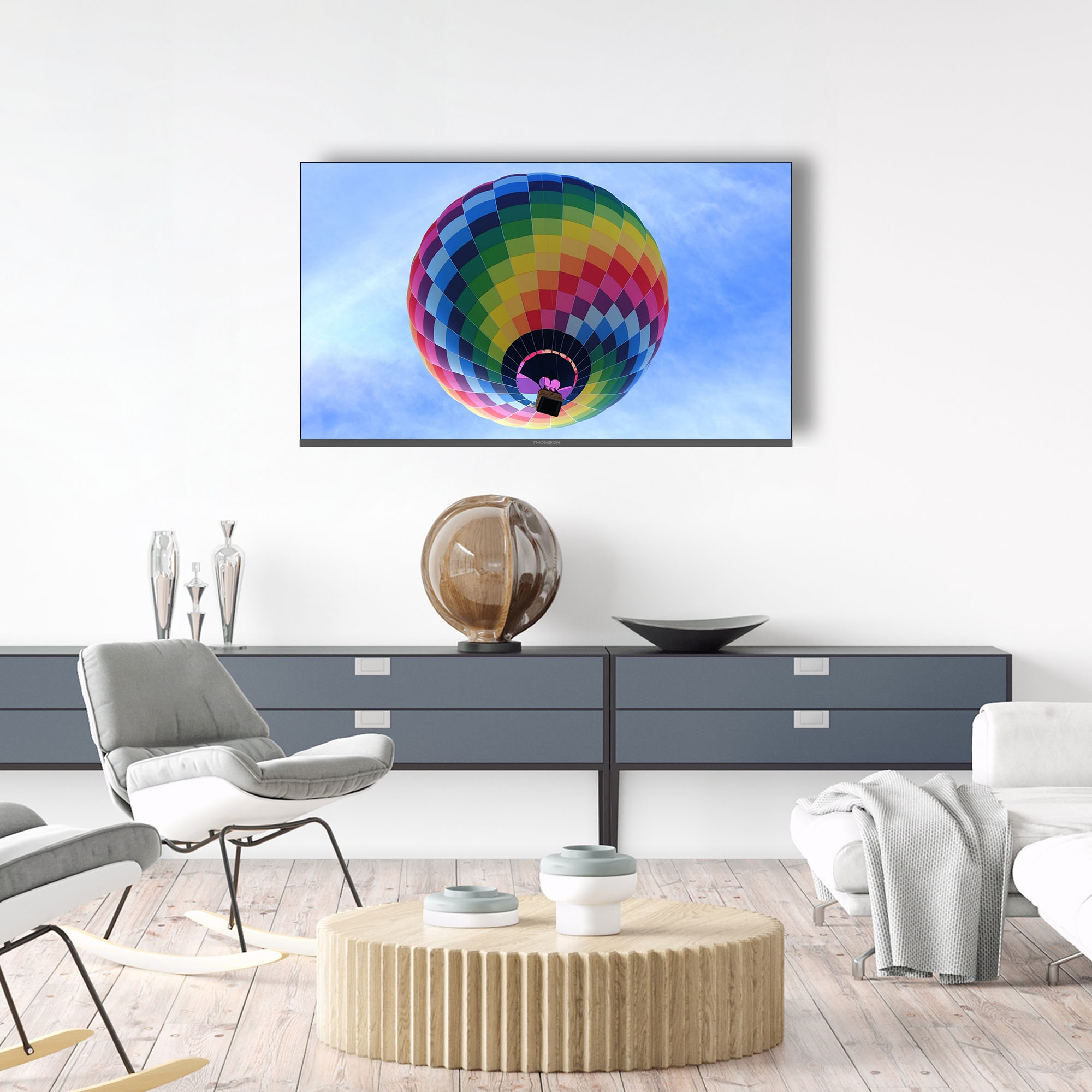 Woonkamer met tv met luchtballon. Meubels: bank, stoelen, tafel.