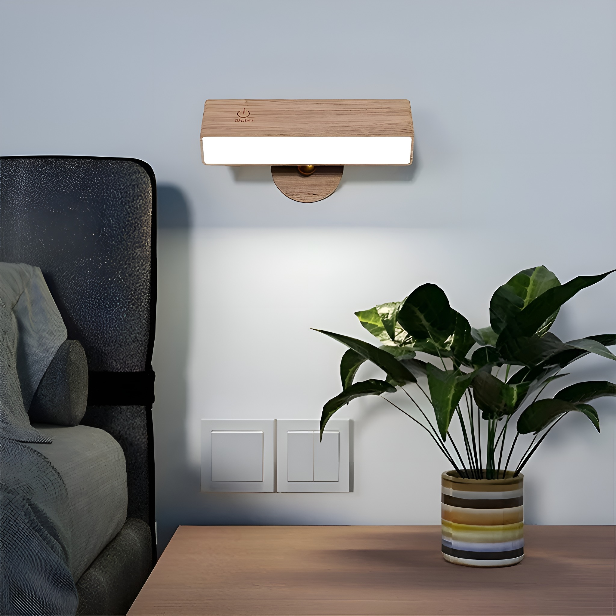 Eine hölzerne Wandlampe mit Pflanze und Bett im Hintergrund, neben einem Schalter.