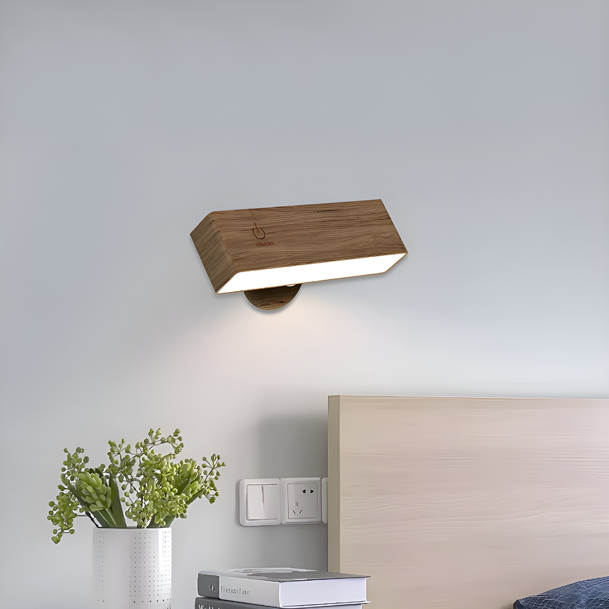 Eine hölzerne Wandleuchte an einer Wand, mit einem weißen Bett und Nachttisch im Bild.