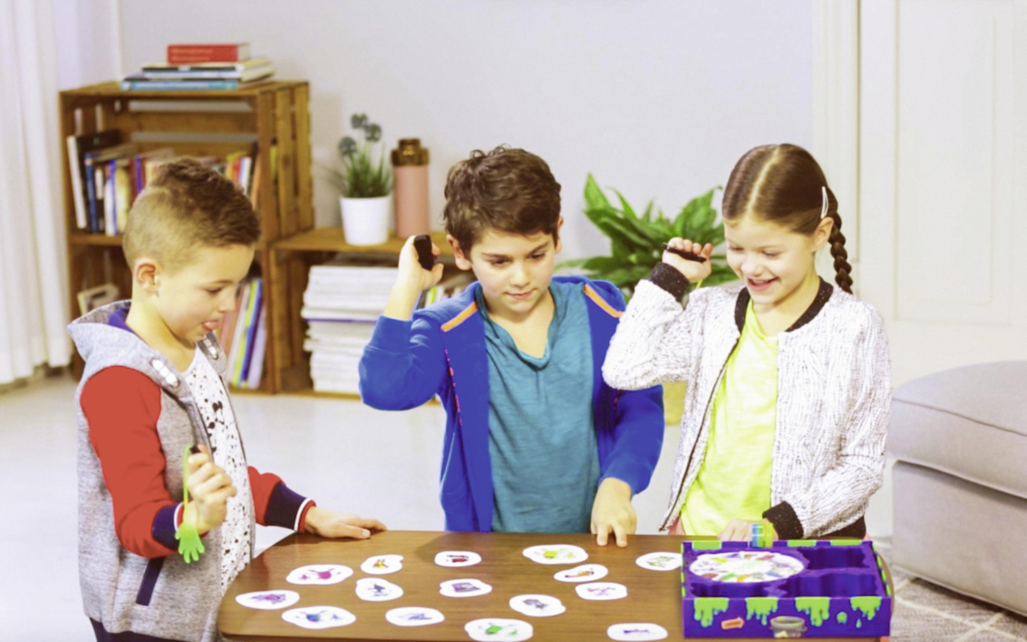 Drei Kinder spielen ein Spiel mit Karten und einem Glücksrad.
