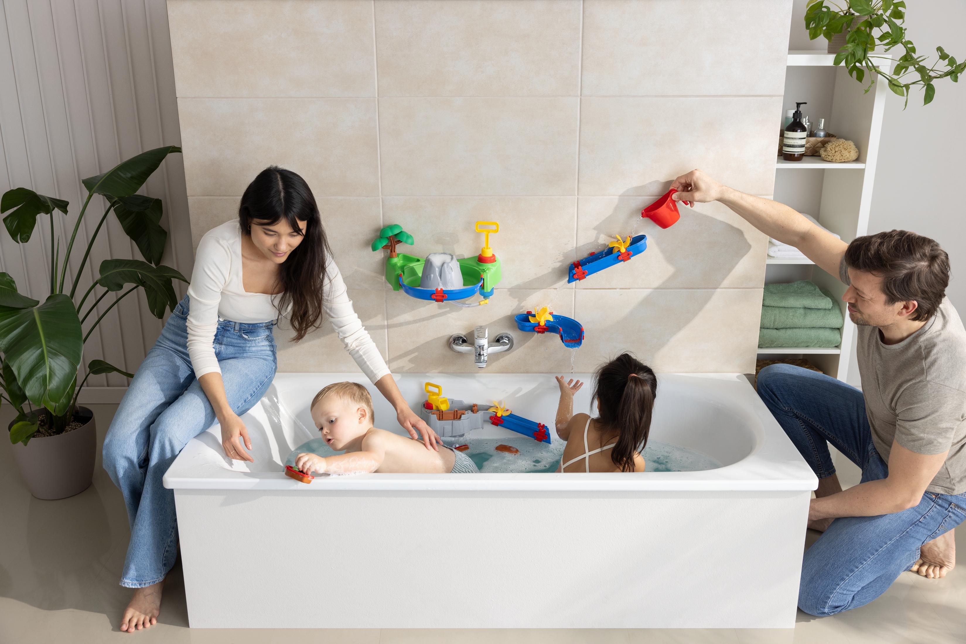 Familie spielt im Badezimmer mit Spielzeug. Baby in der Wanne mit Eltern in der Nähe.