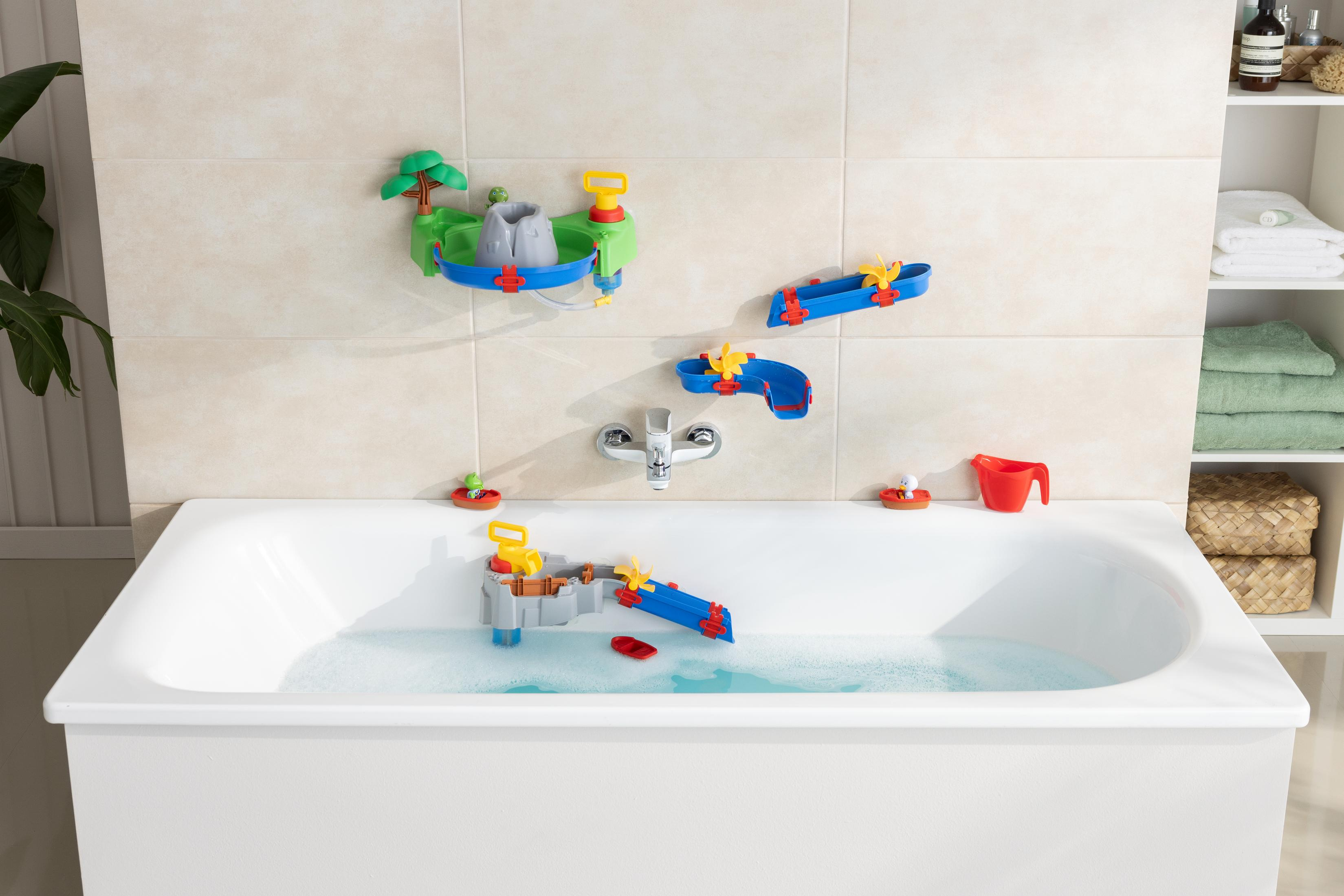 Badewanne mit an der Wand befestigtem Wasserspielzeug, darunter ein Vulkan, eine Wasserrutsche und ein roter Becher.