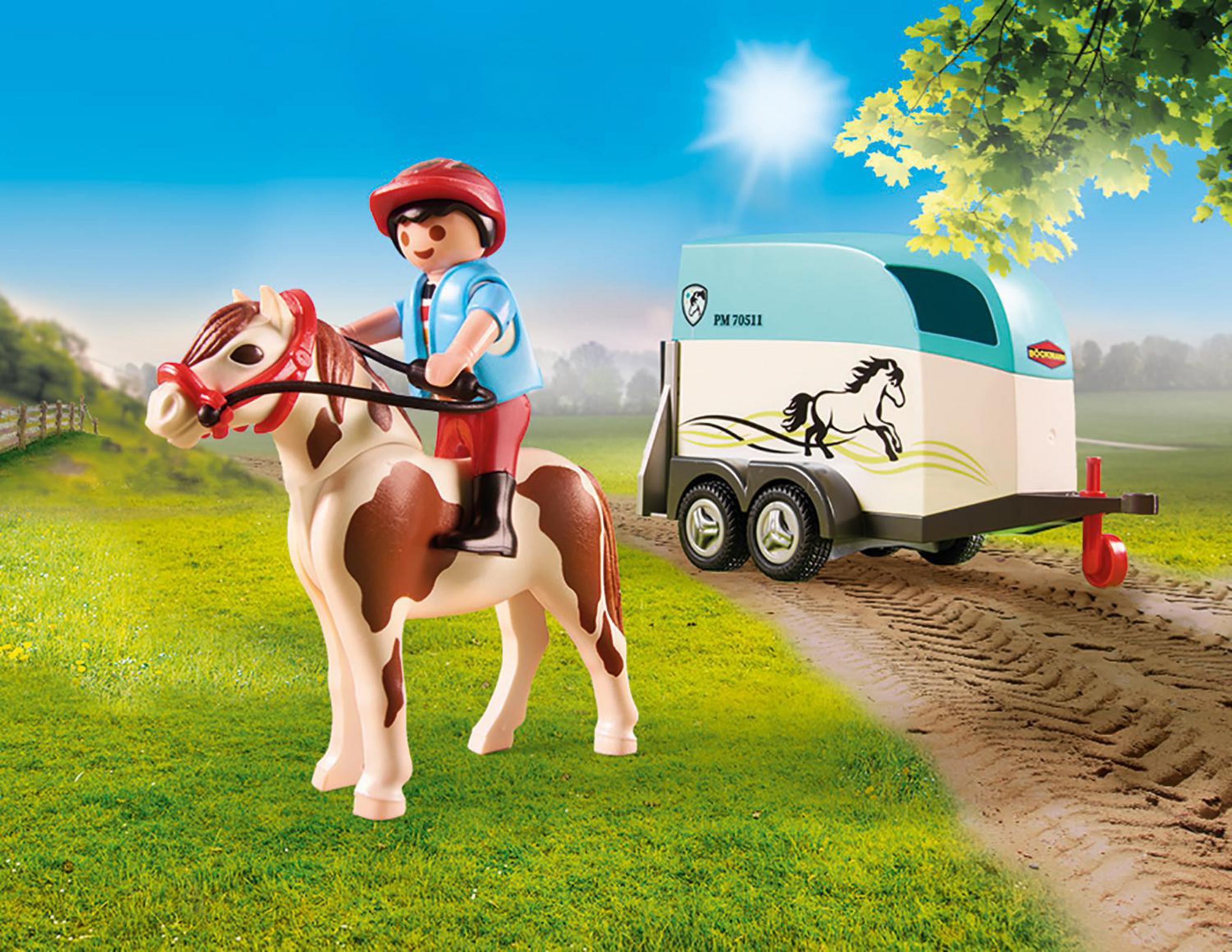Cheval et remorque jouets. Une figurine monte le cheval. Herbe verte et ciel bleu en arrière-plan.