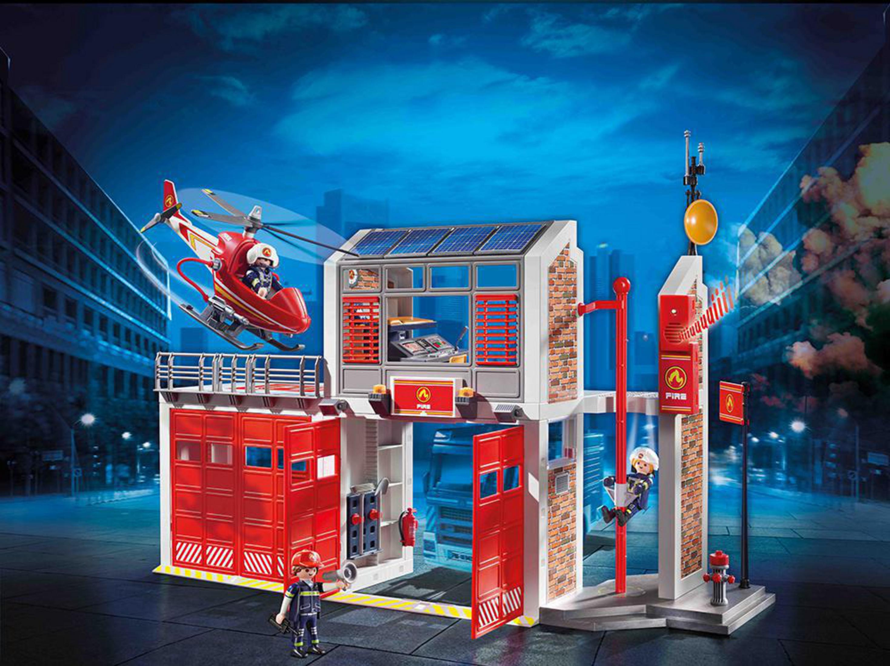 Una scena della stazione dei pompieri Playmobil con un elicottero in aria e un pompiere che scende da un palo.