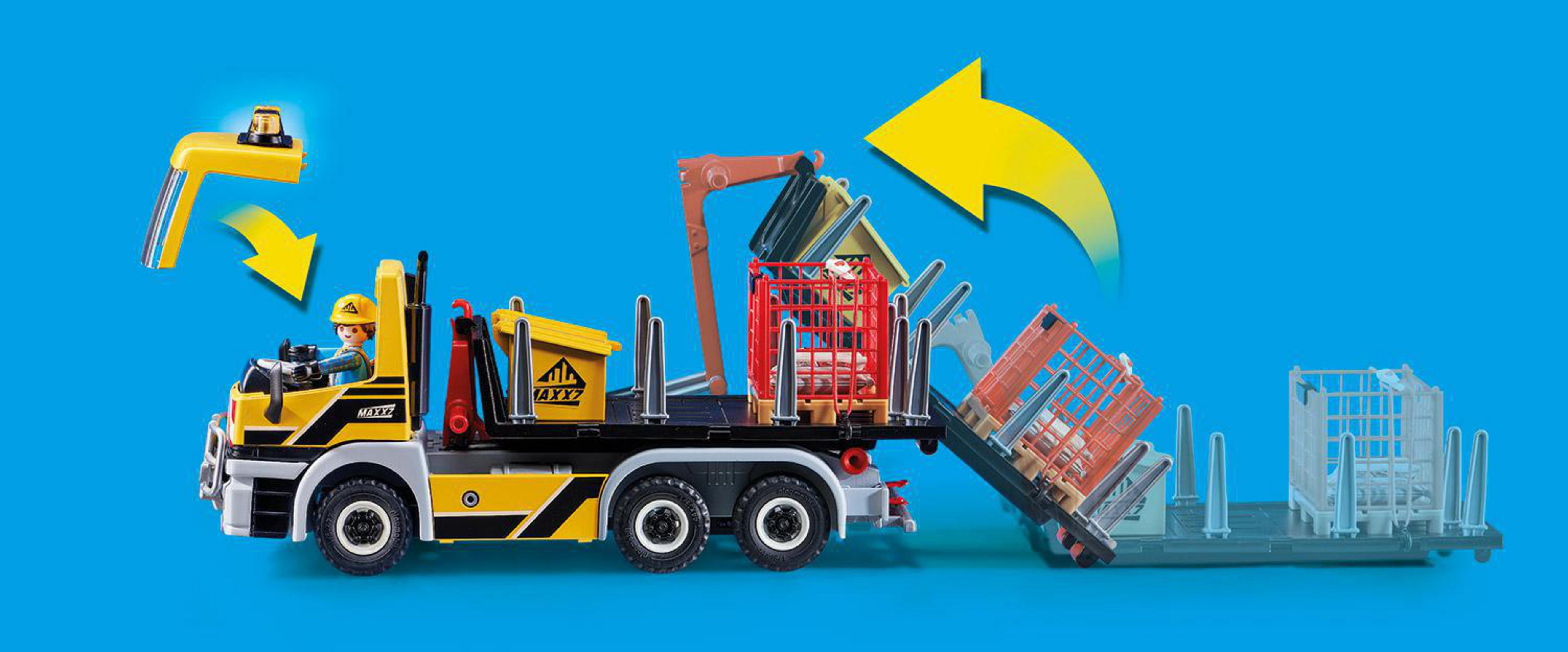 Ein LKW-Spielzeug transportiert einen Kran, einen Arbeiter und verschiedene Baumaterialien auf blauem Grund.