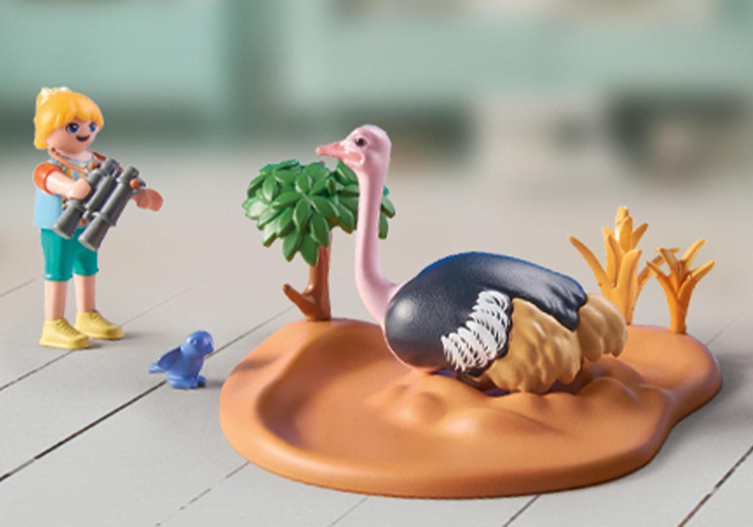 Eine Spielzeugszene mit einem Strauß, einer Person mit Fernglas und einem kleinen blauen Vogel.