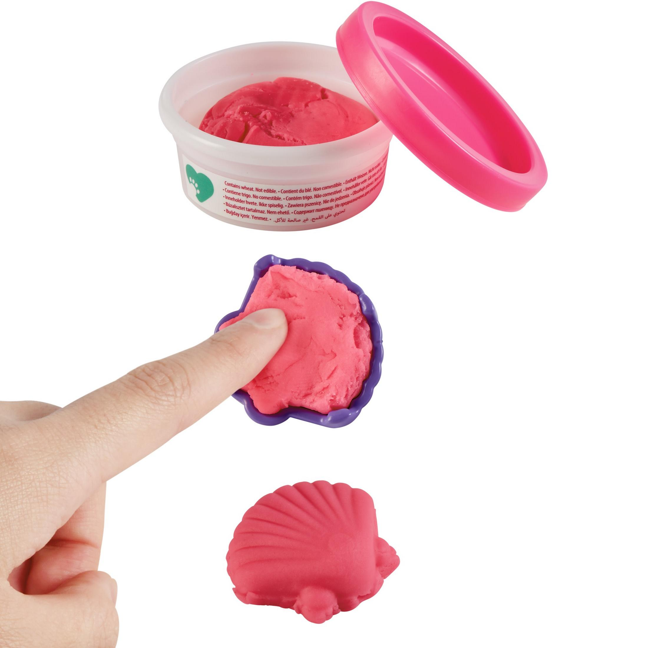 Różowa plastelina z ręką wciskającą ją w formę w kształcie muszli.