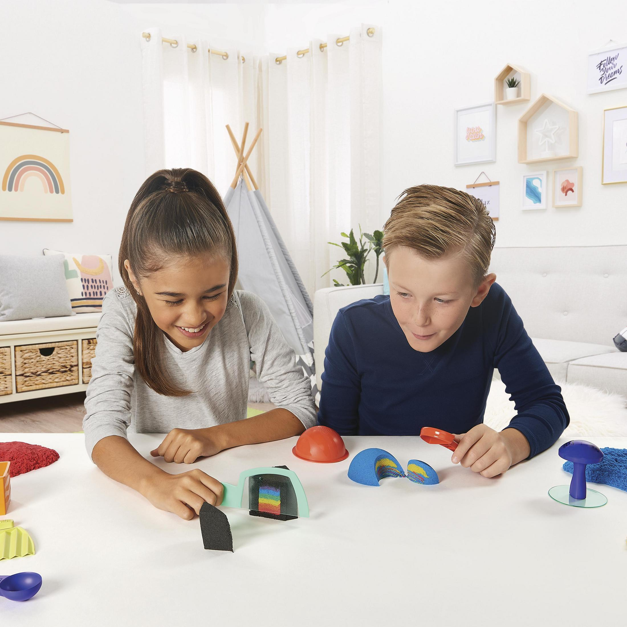 Deux enfants jouant à un jeu sur une table. Diverses pièces du jeu sont visibles.