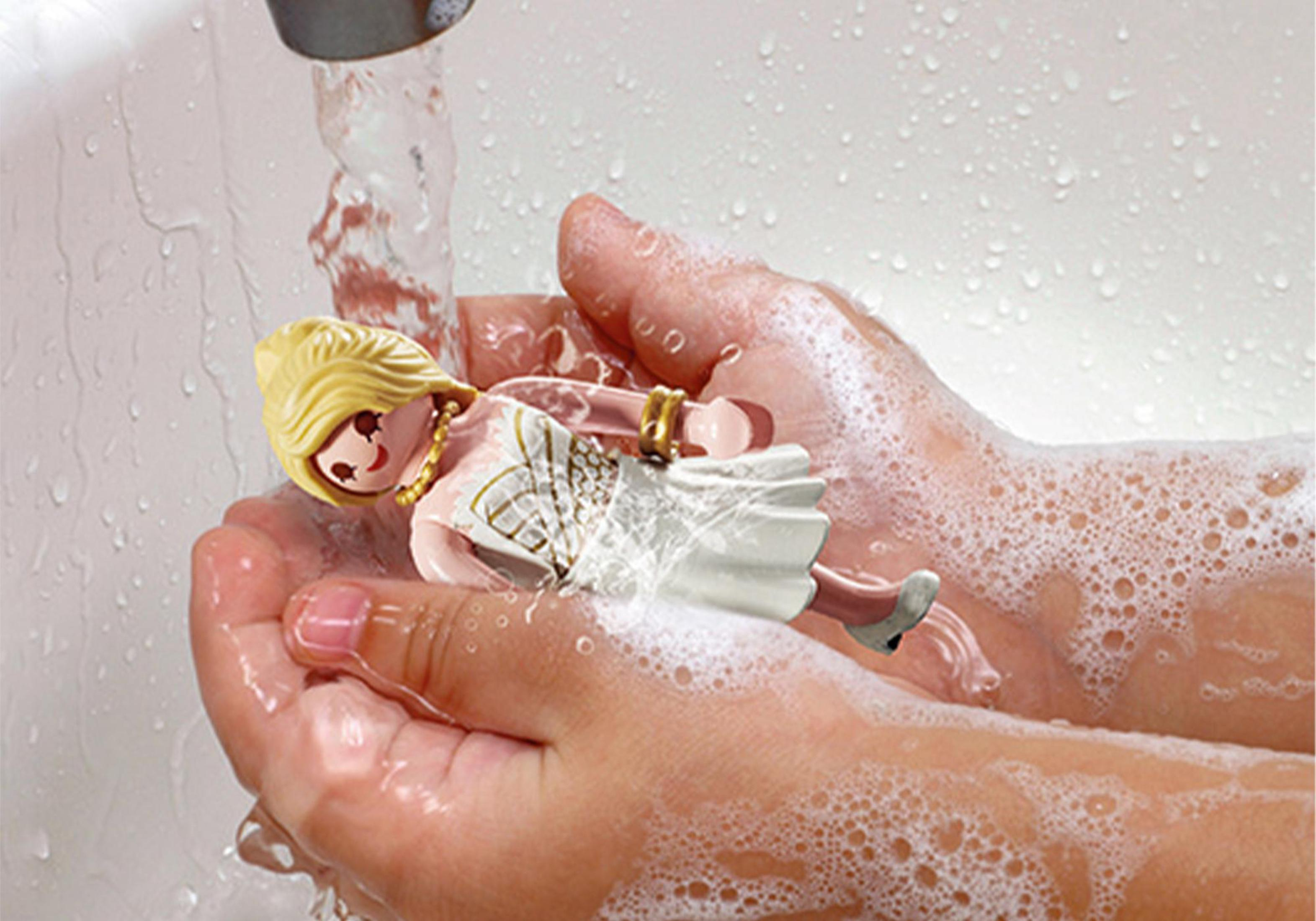 Dłonie myjące zabawkę pod bieżącą wodą z pianą mydlaną.