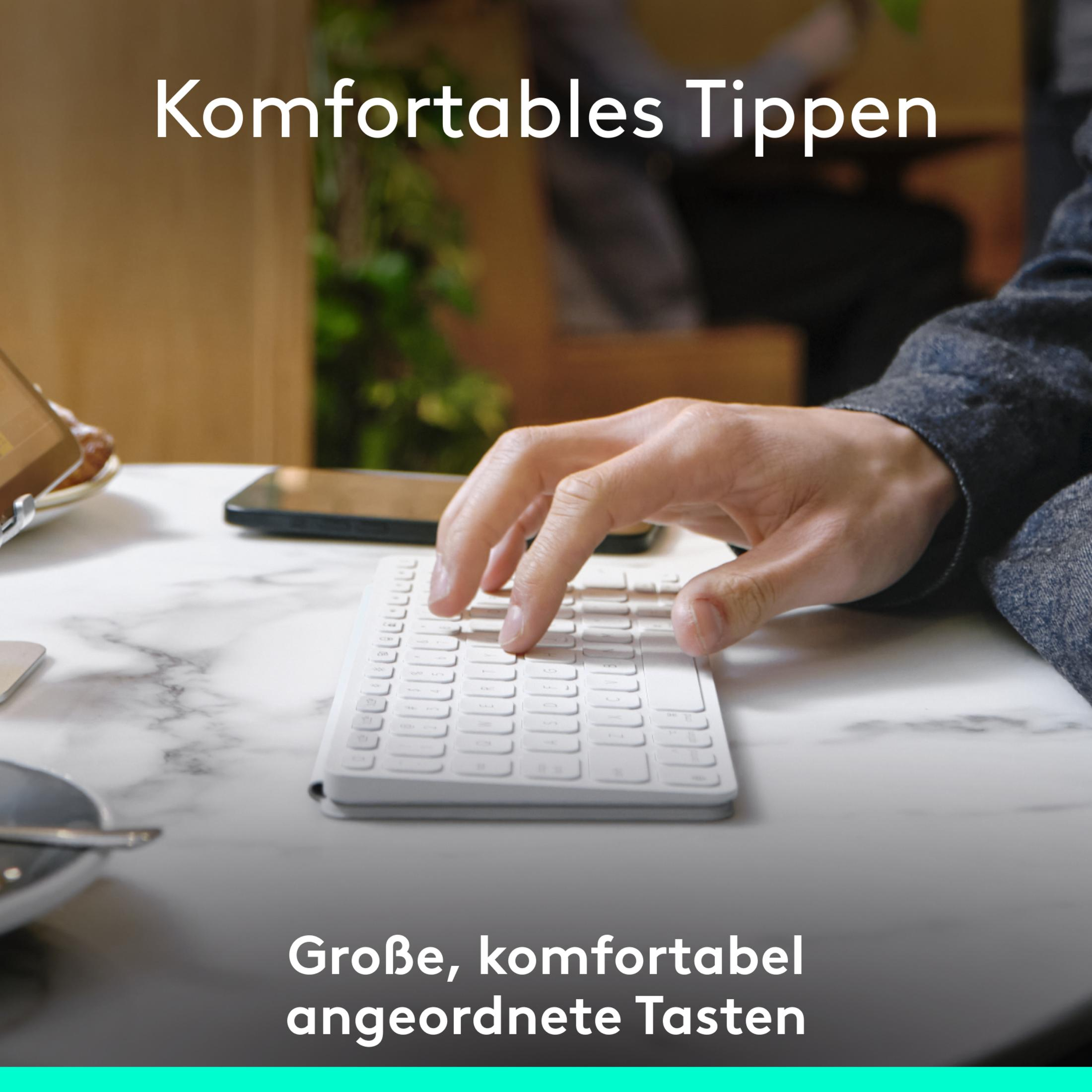 Person tippt auf einer weißen Tastatur. Das Bild enthält ein Telefon, einen Schreibtisch und eine Tasse.