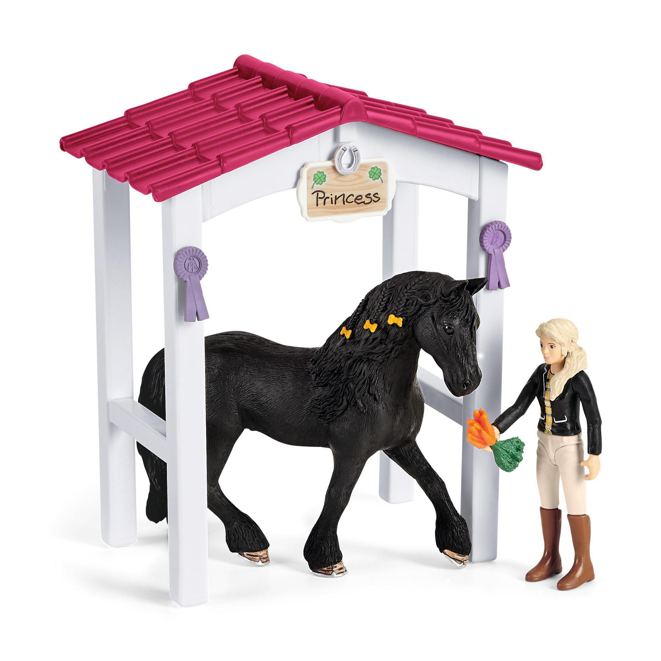 Ein Spielzeugpferd unter einem Stall. Ein Mädchen hält Karotten. Das Pferd ist schwarz.