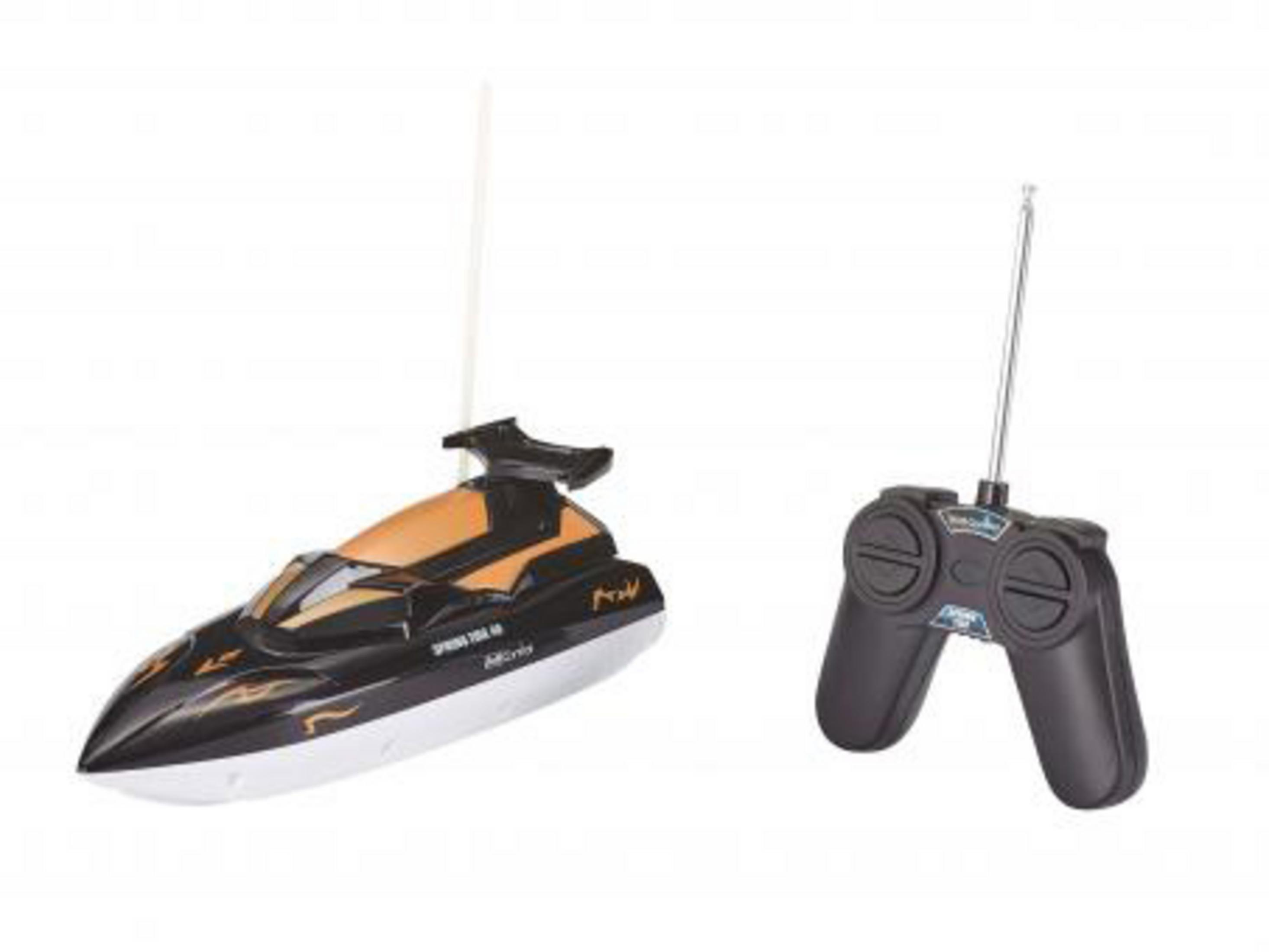 Un barco y controlador con control remoto, el barco es negro y naranja con una aleta.