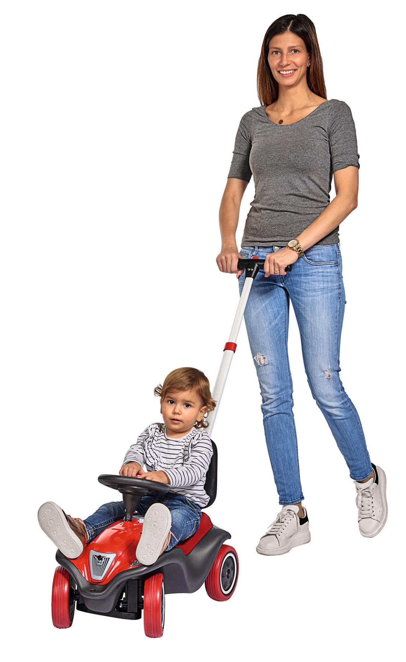 Kobieta pcha czerwony samochodzik z dzieckiem. Oboje na białym tle.
