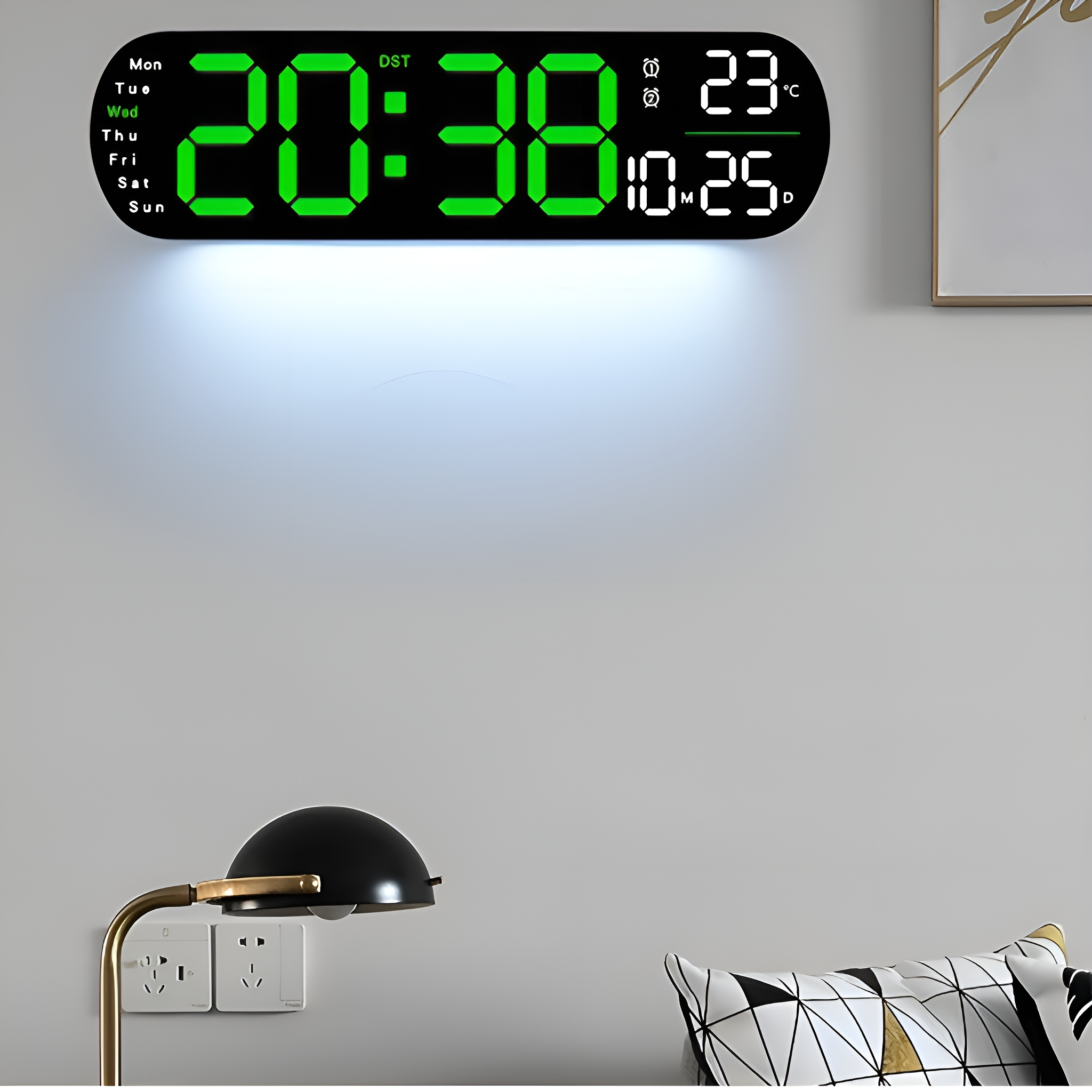 Eine digitale Wanduhr, die die Uhrzeit und den Wochentag anzeigt, über einer Lampe und einem Kissen.