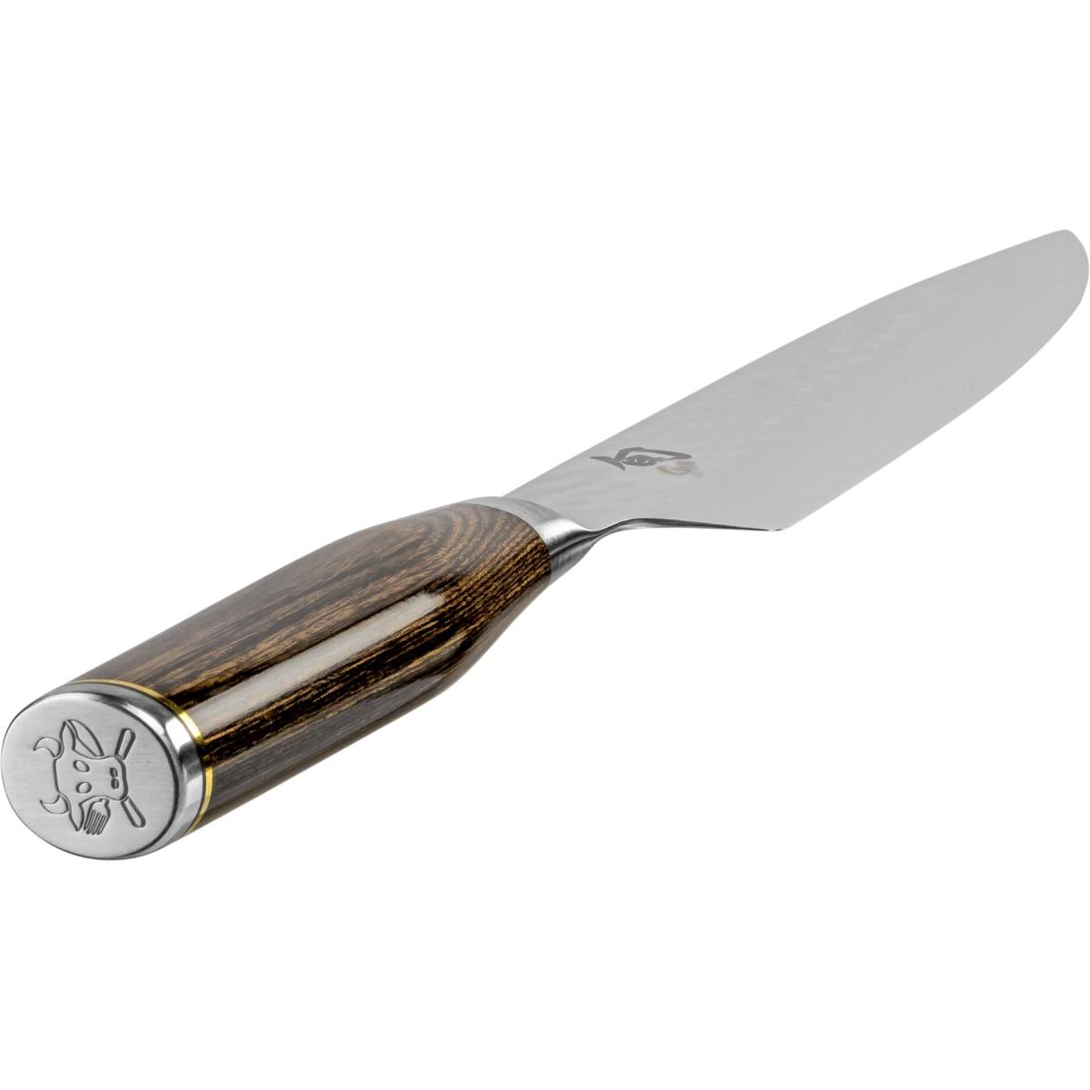 Un cuchillo de cocina con mango de madera y hoja plateada. Está sobre un fondo blanco.