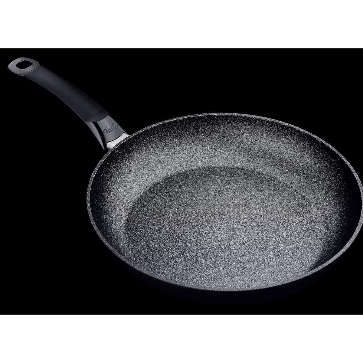 Una padella nera con manico nero su sfondo nero.