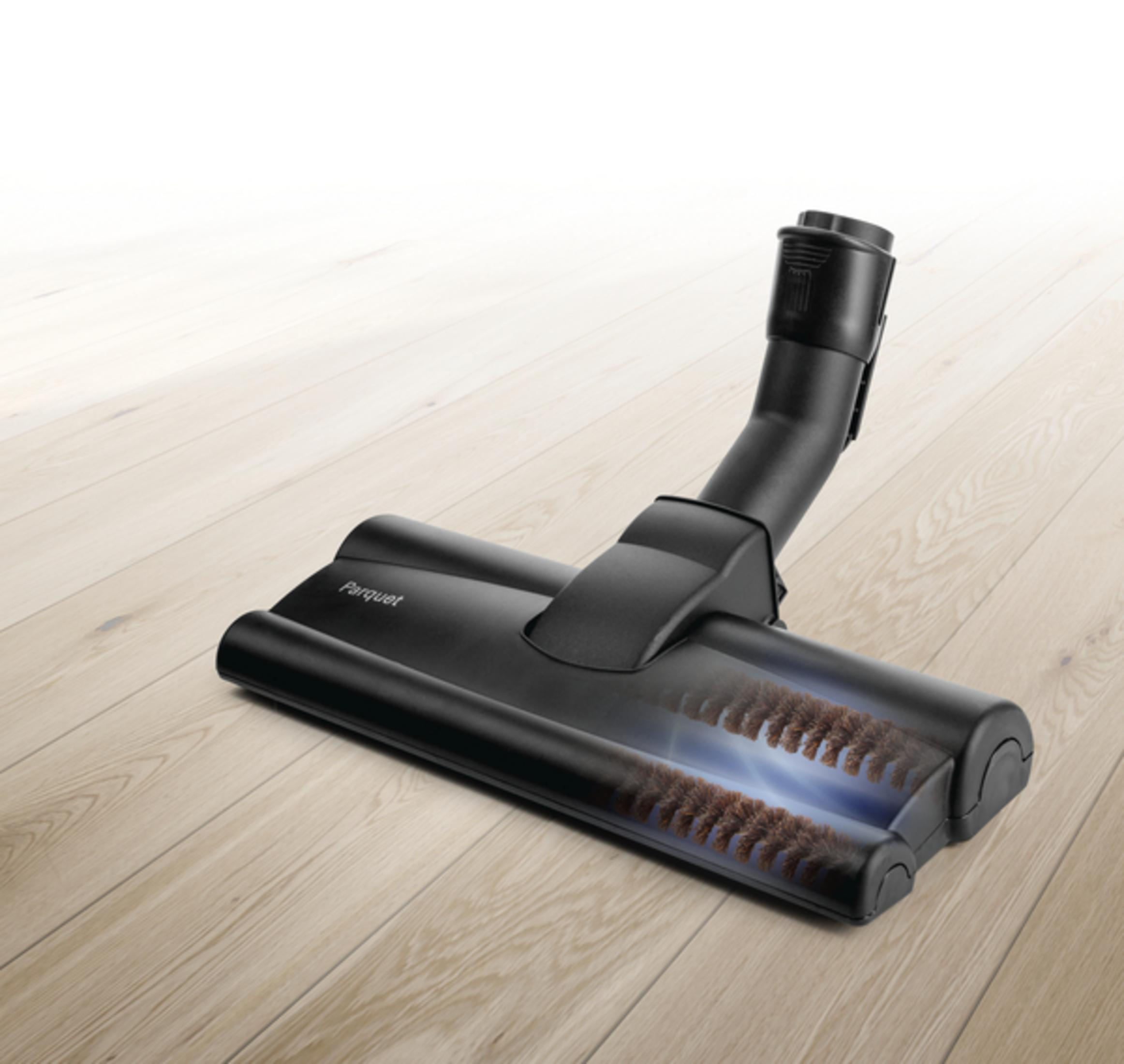 Schwarzer Staubsaugerkopf mit Parquet-Aufschrift. Er liegt auf einem Holzboden. Der Boden ist hellbraun.