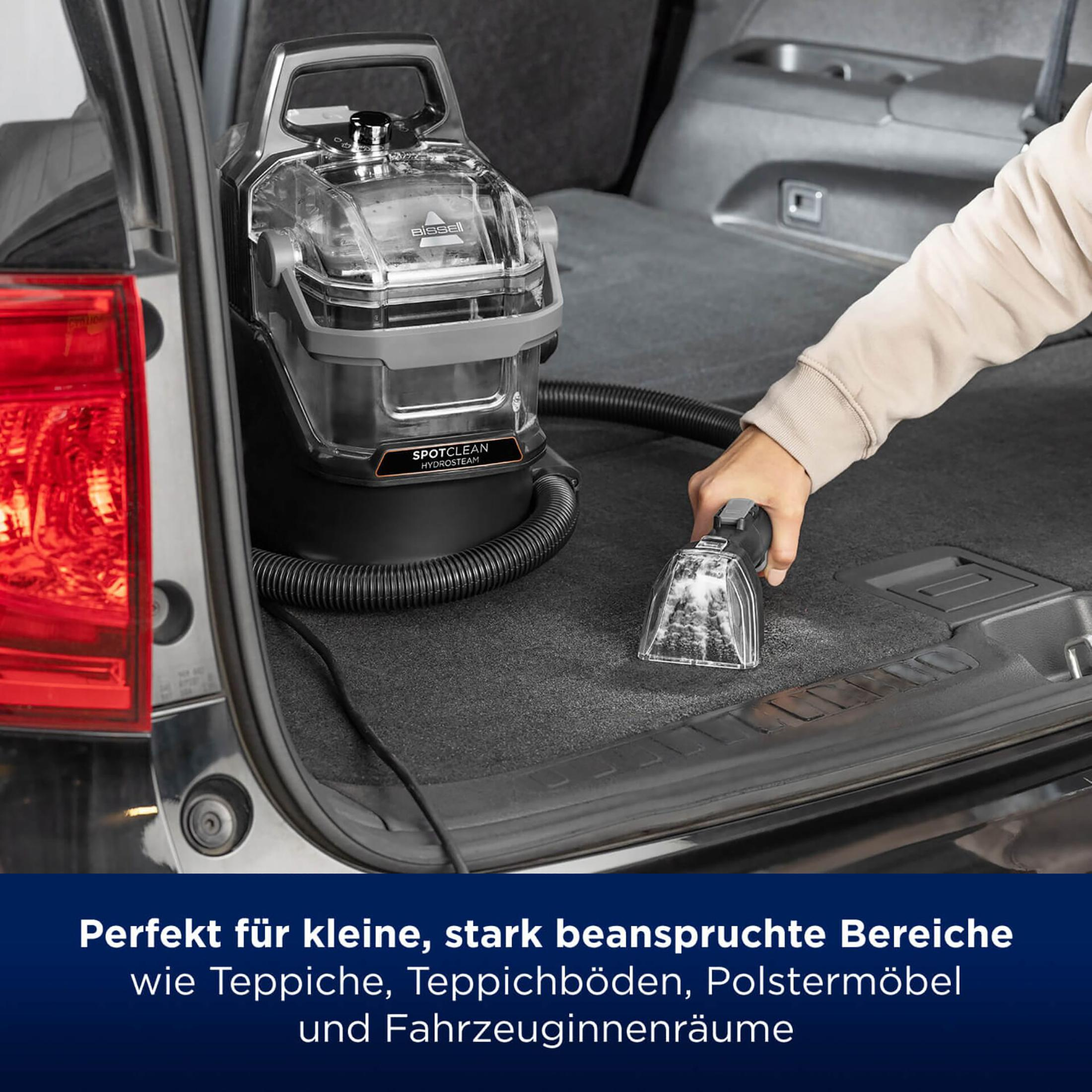 Hand benutzt einen Handstaubsauger im Kofferraum eines Autos, reinigt eine Teppichoberfläche.