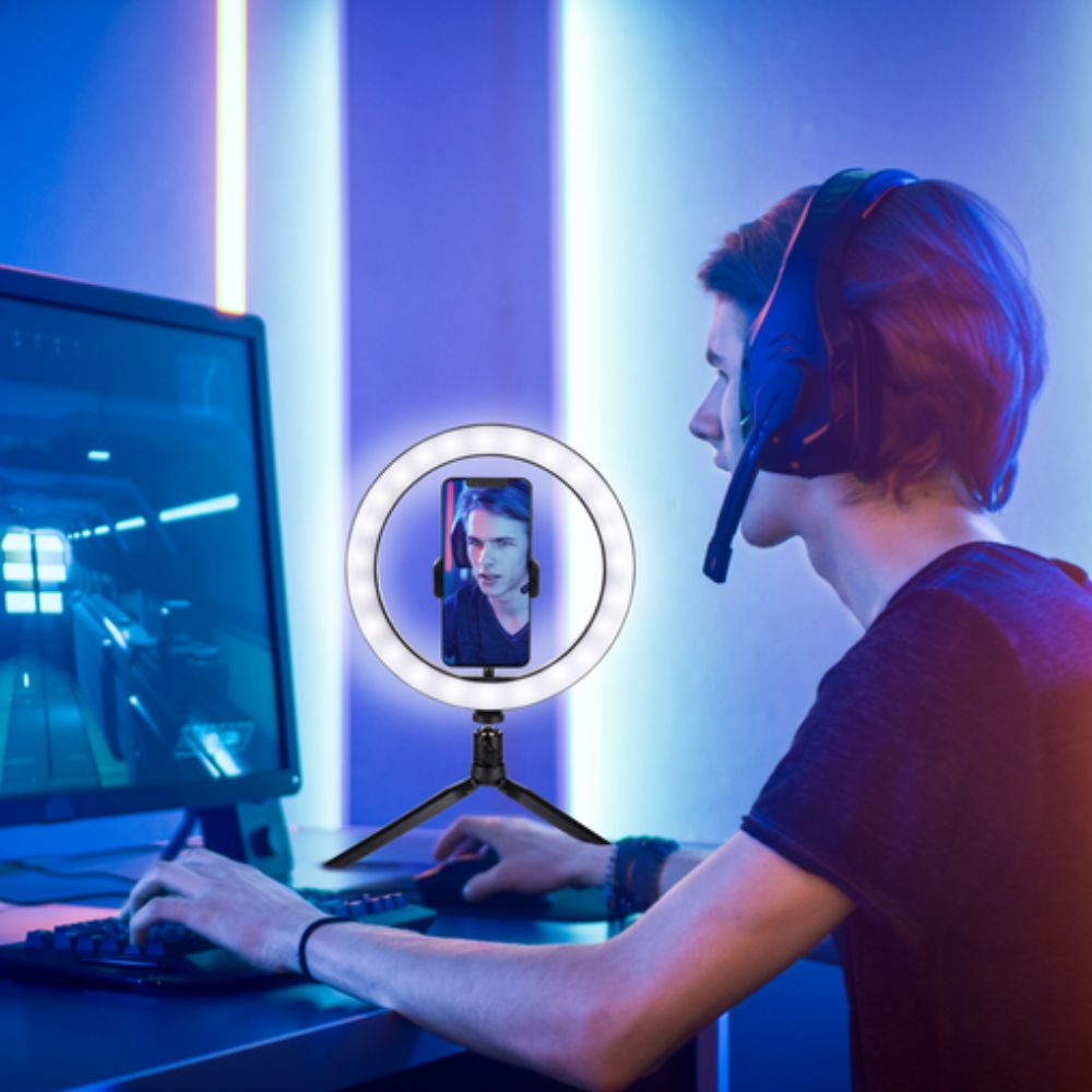 Homme utilisant une lampe annulaire avec un téléphone pour le streaming. Il porte un casque.