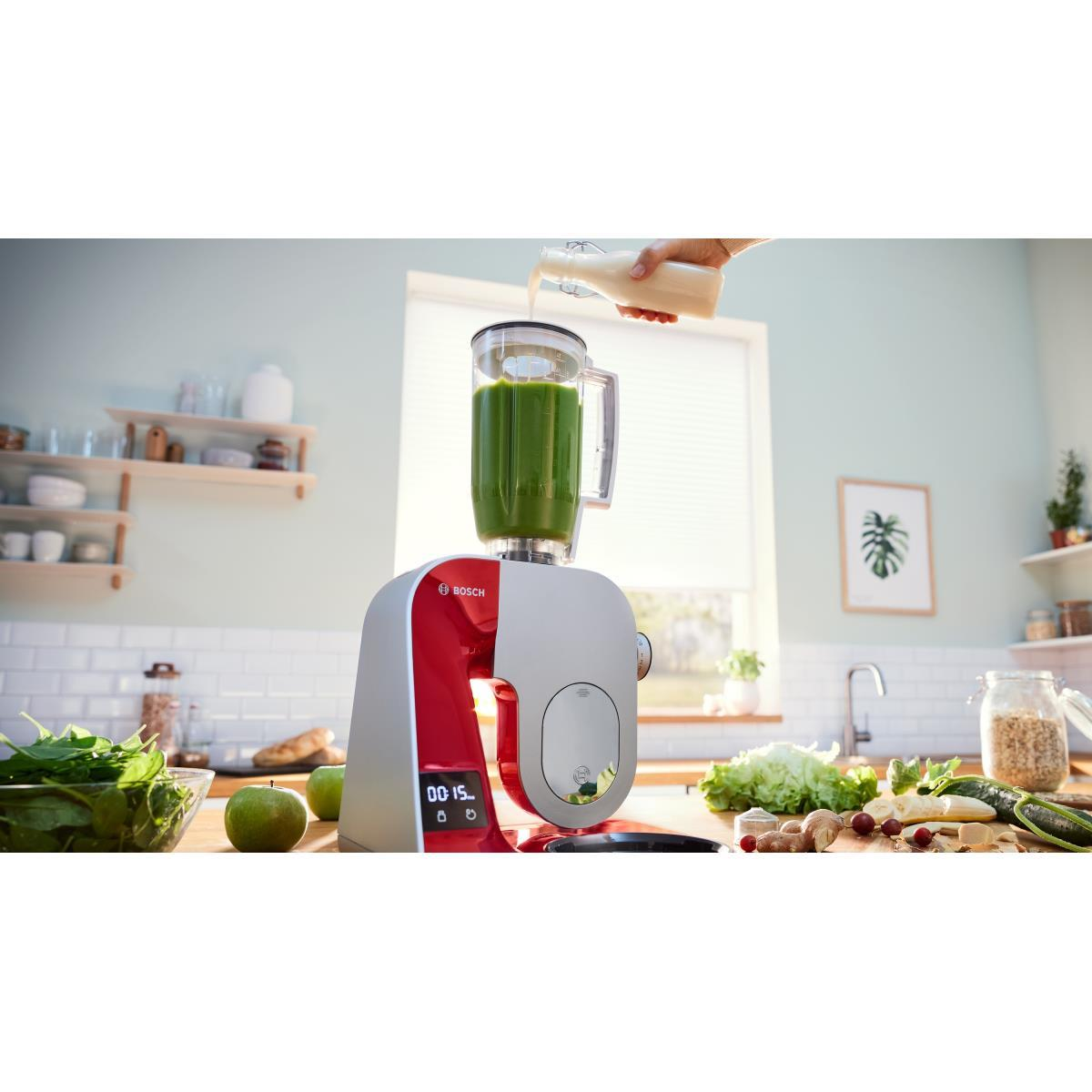 Eine rote und silberne Küchenmaschine mit einem Mixer und einer Hand, die Flüssigkeit eingießt.