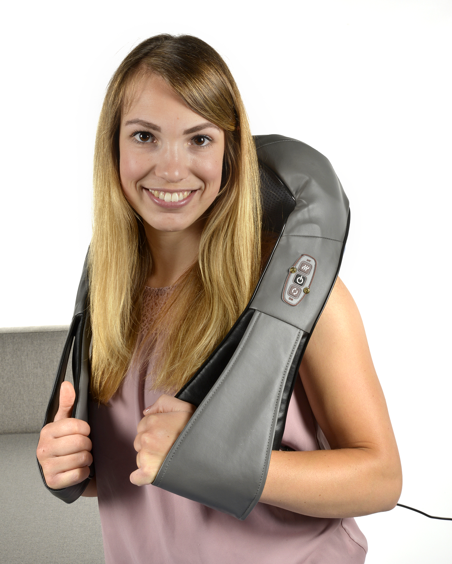 A woman is wearing a gray neck massager and smiling at the camera.