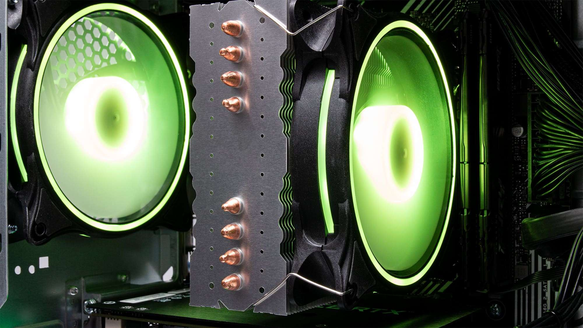 Computerlüfter mit grünen Lichtern und Kupfer-Heatpipes in einem Gehäuse.
