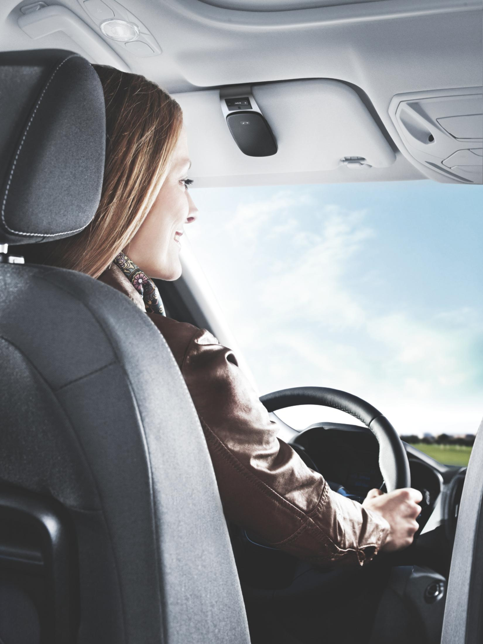 Frau fährt Auto. Sie lächelt. Auto-Innenraum und Außenansicht.