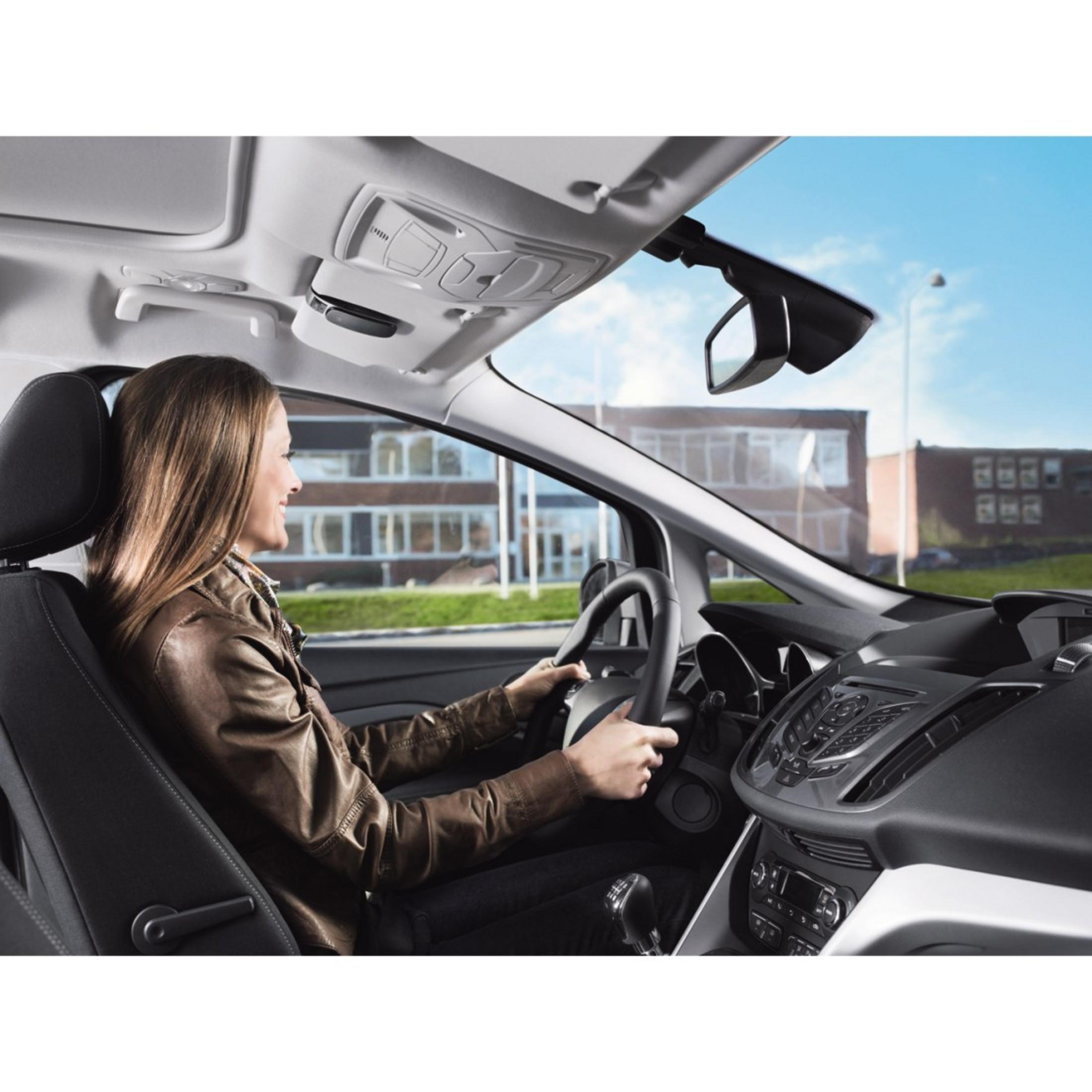 Eine Frau fährt Auto, von innen gesehen, Armaturenbrett und Straße sind sichtbar.